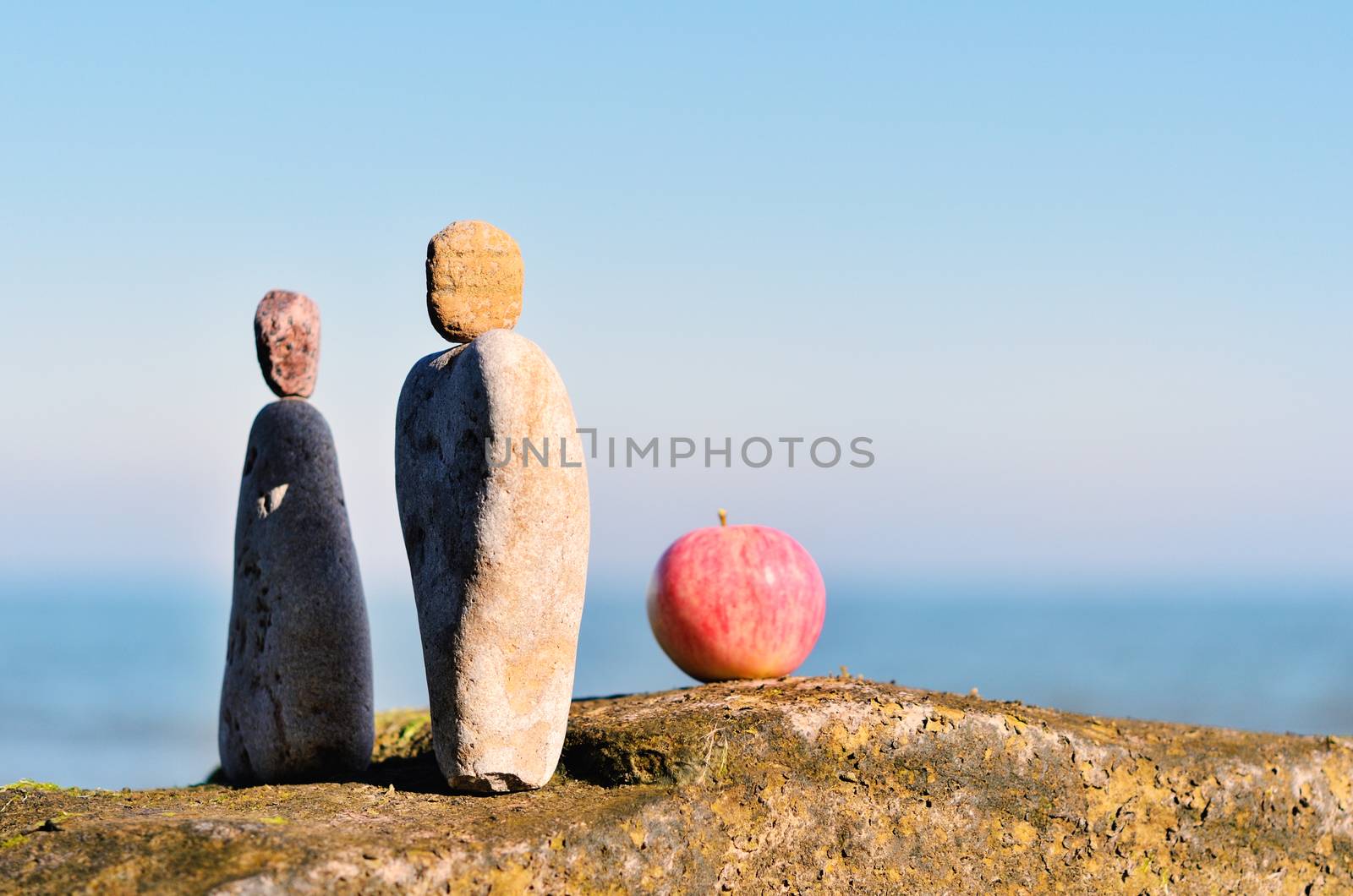 Balancing of two triangle stones and apple on the seacoast