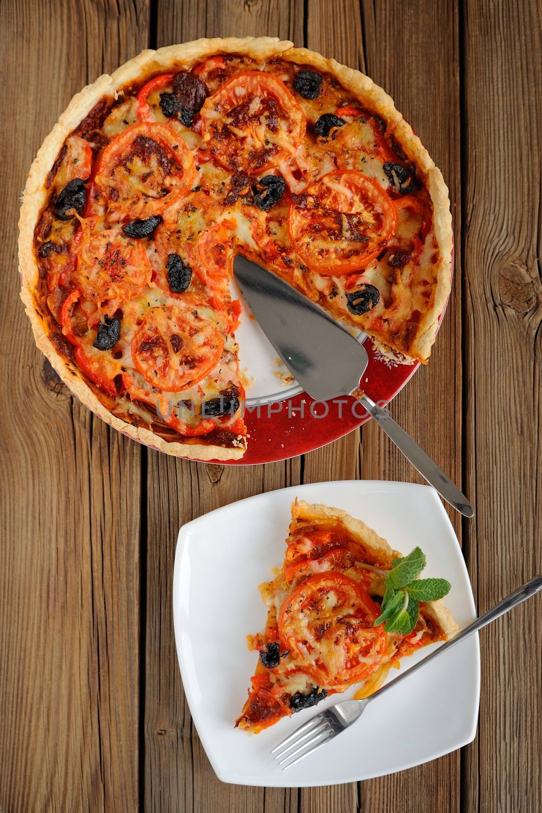 Tomato tart with olives on wooden background vertical