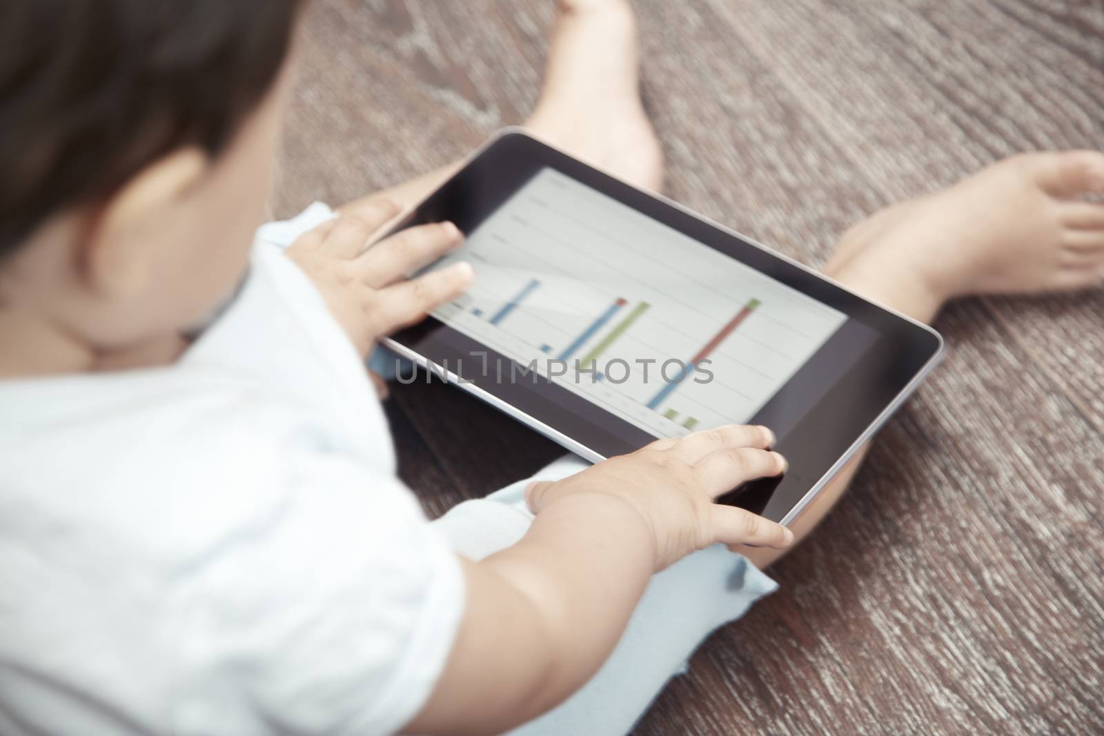 Child holding tablet computer with business chart