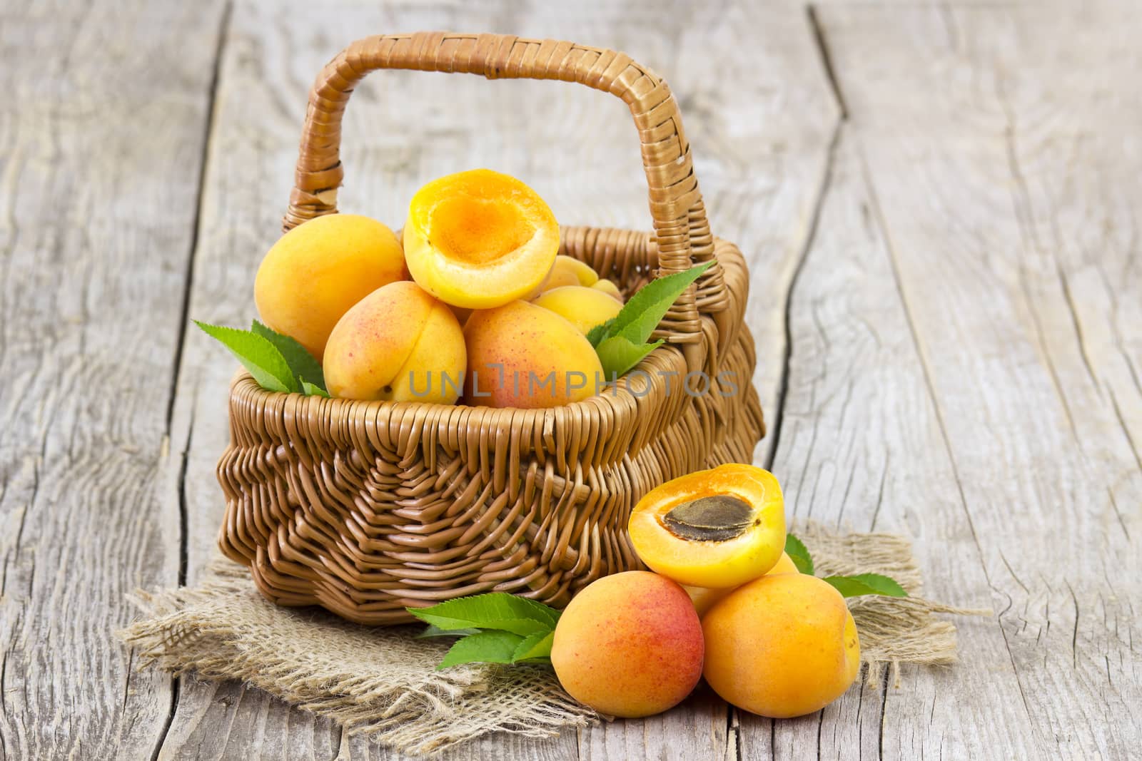 fresh apricots in a basket on wooden background by miradrozdowski