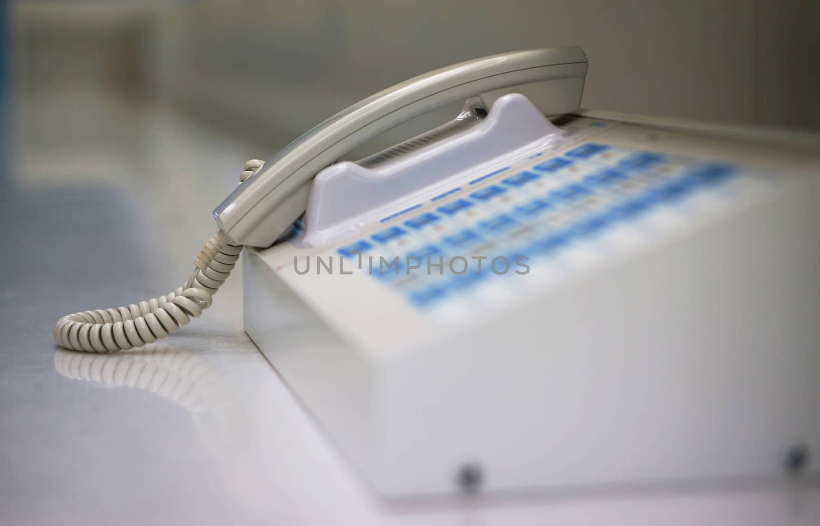 White phone to communicate in the office, placed at the front counter.                               