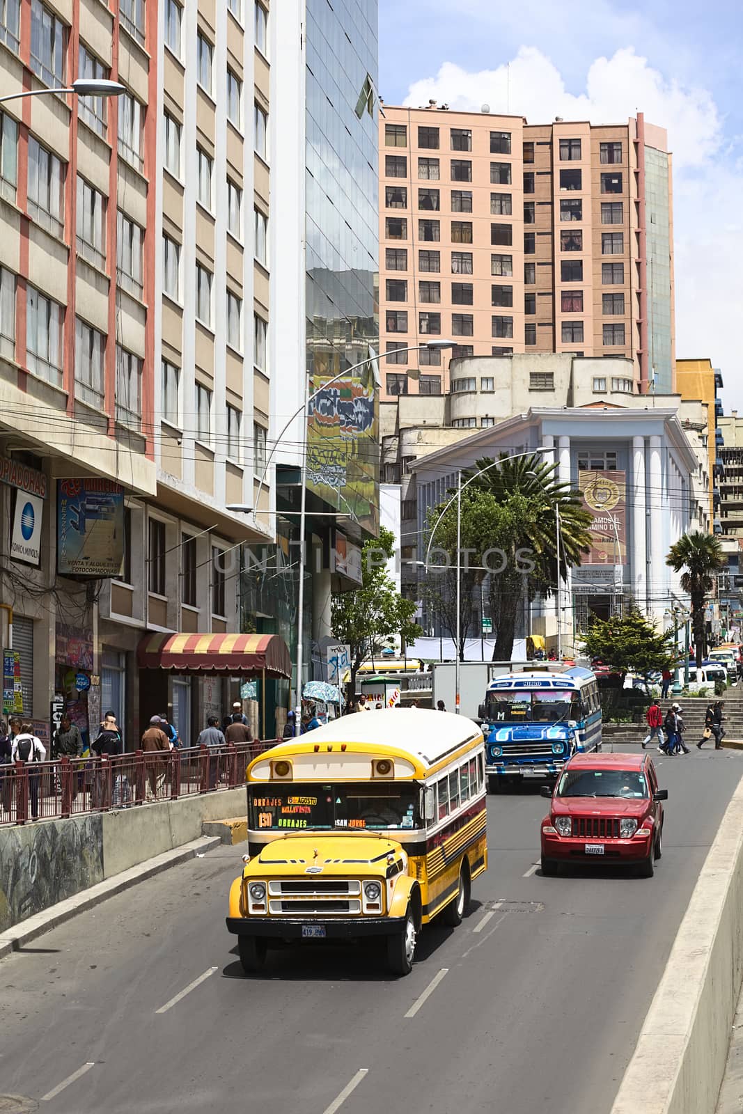 LA PAZ, BOLIVIA - NOVEMBER 28, 2014: Old Chevrolet buses used for public transport and a new Jeep on Villazon Avenue with the Plaza del Estudiante (Student's Square) in the back in the city center on November 28, 2014 in La Paz, Bolivia 