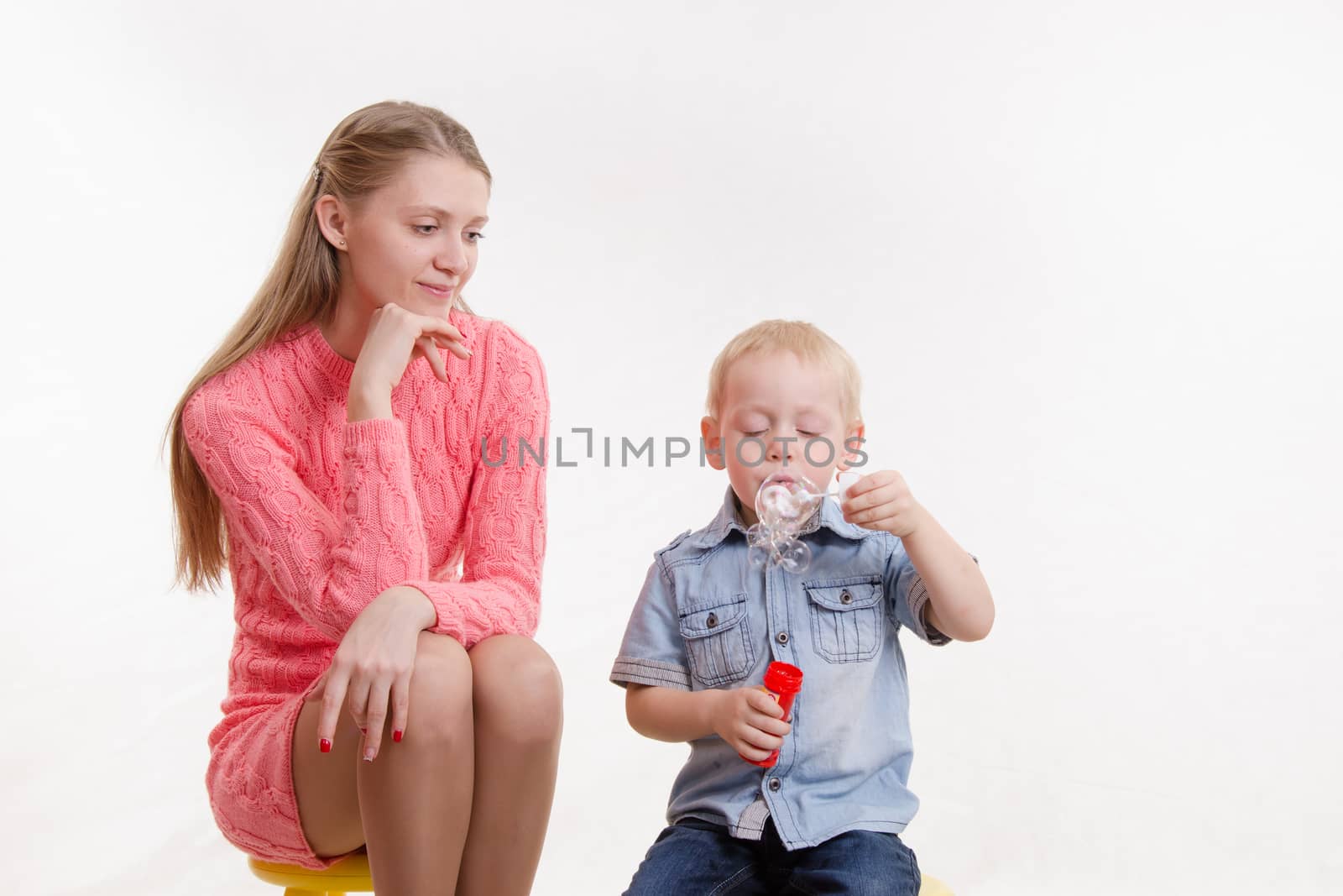 Young mother watching her son who blow bubbles