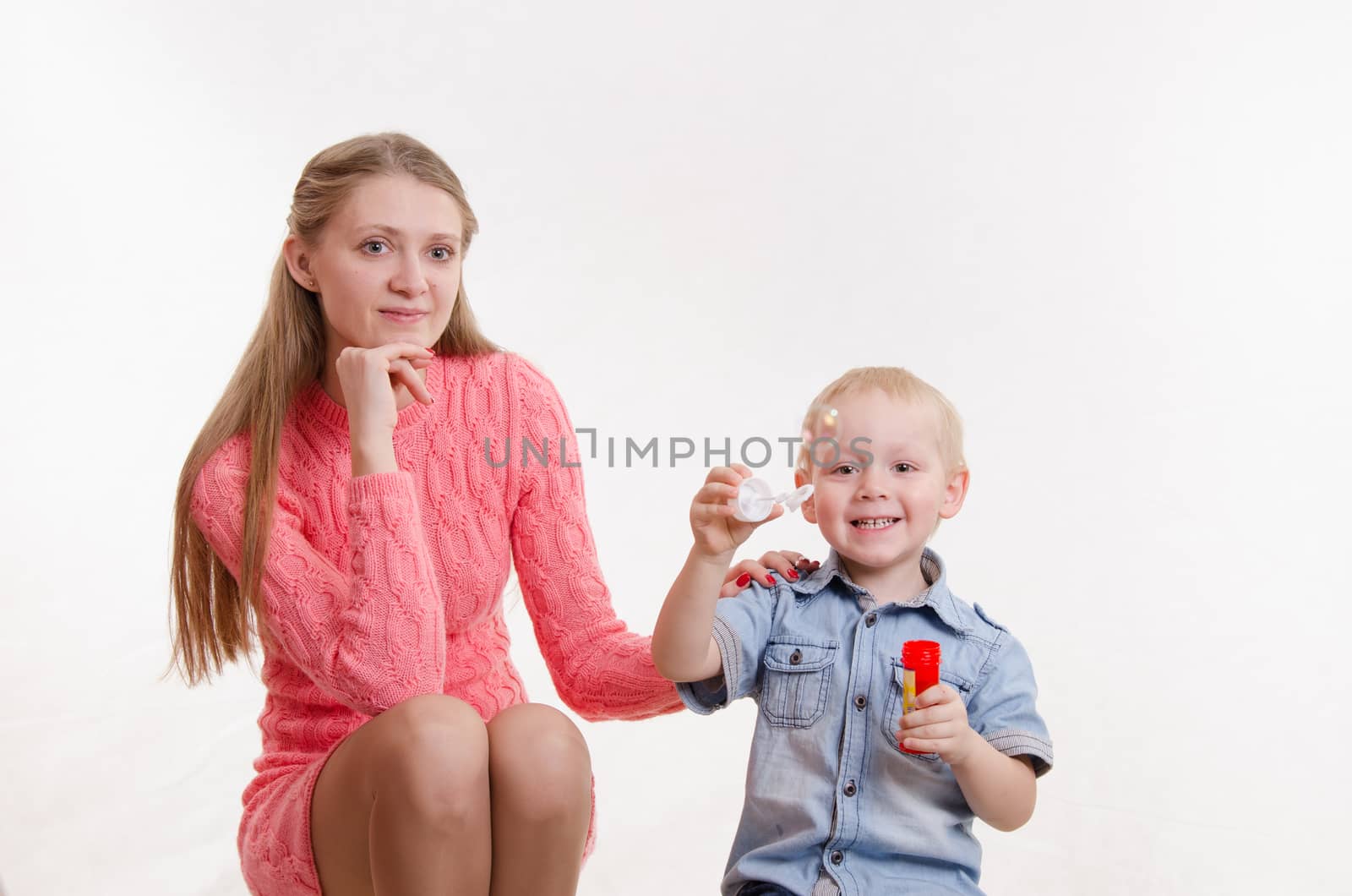 Young mother watching her son who blow bubbles