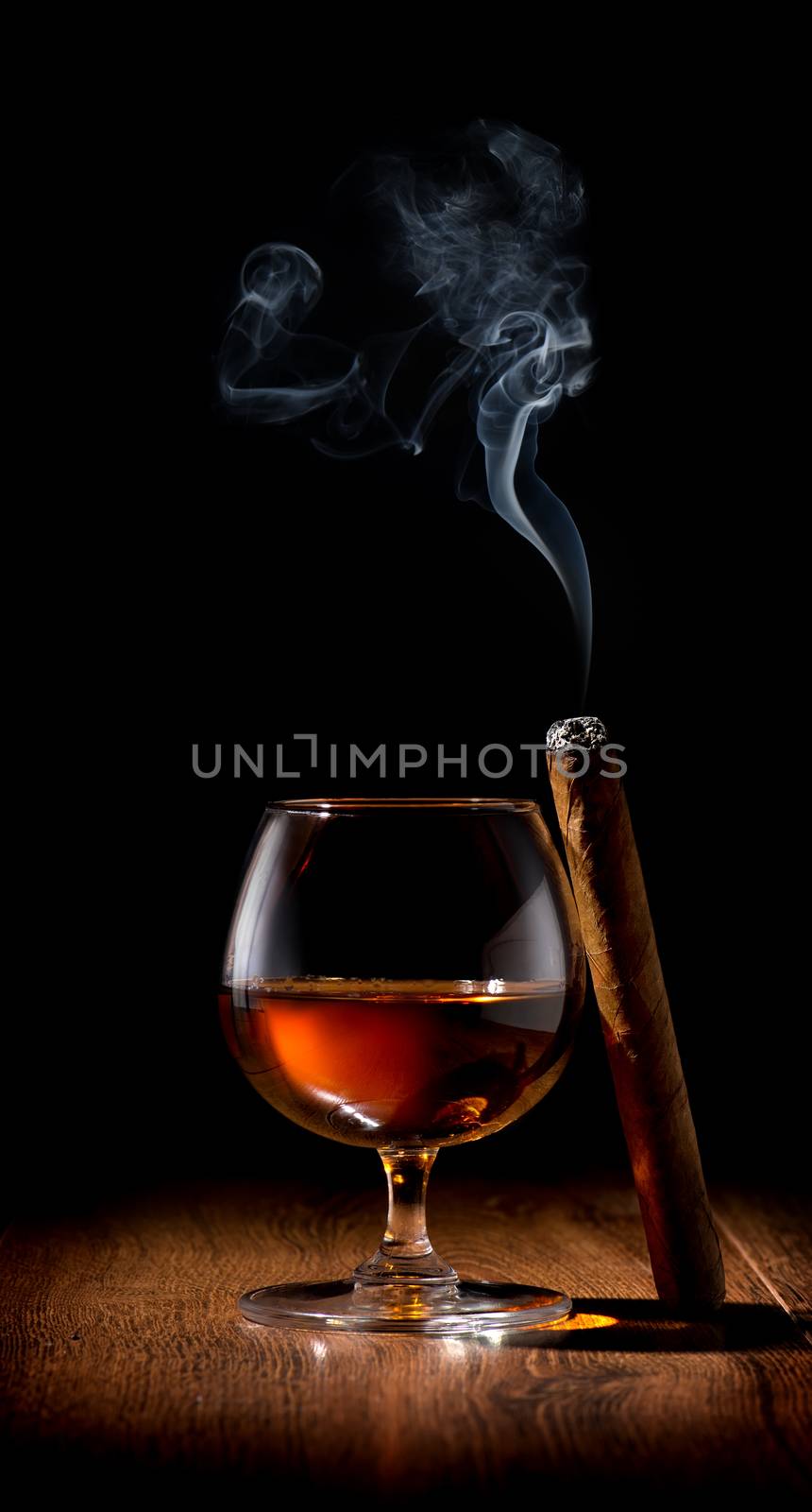 Wineglass of scotch and cigar on wooden table