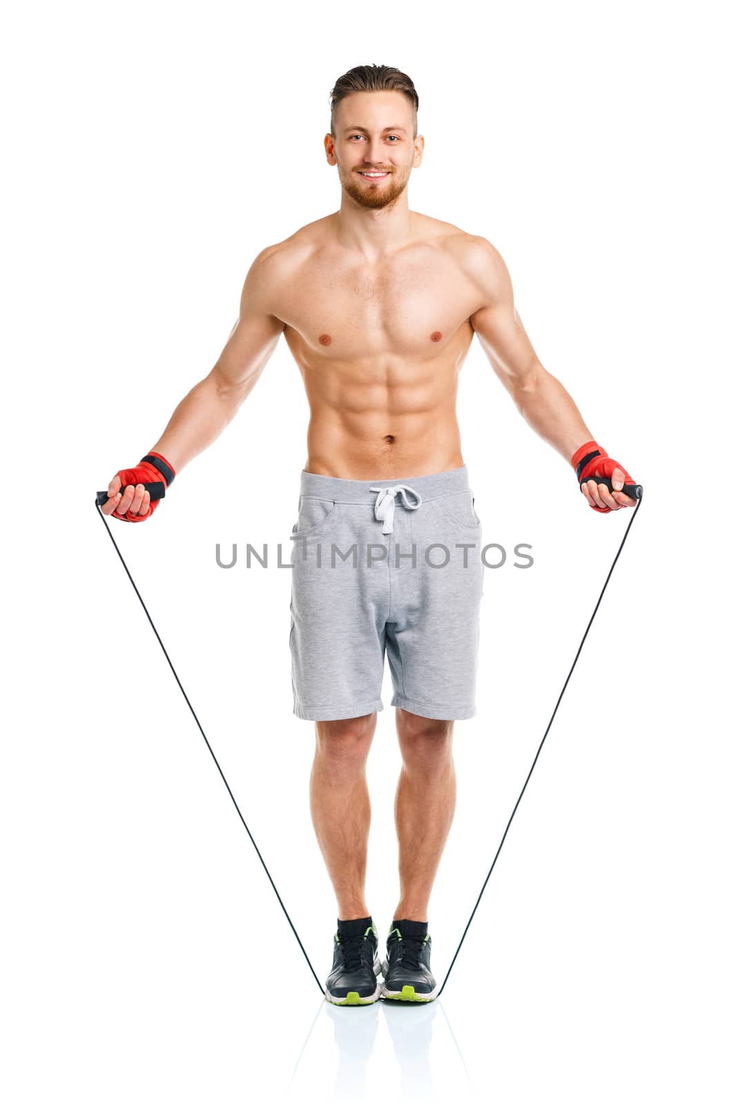 Athletic attractive man jumping on a rope on the white background