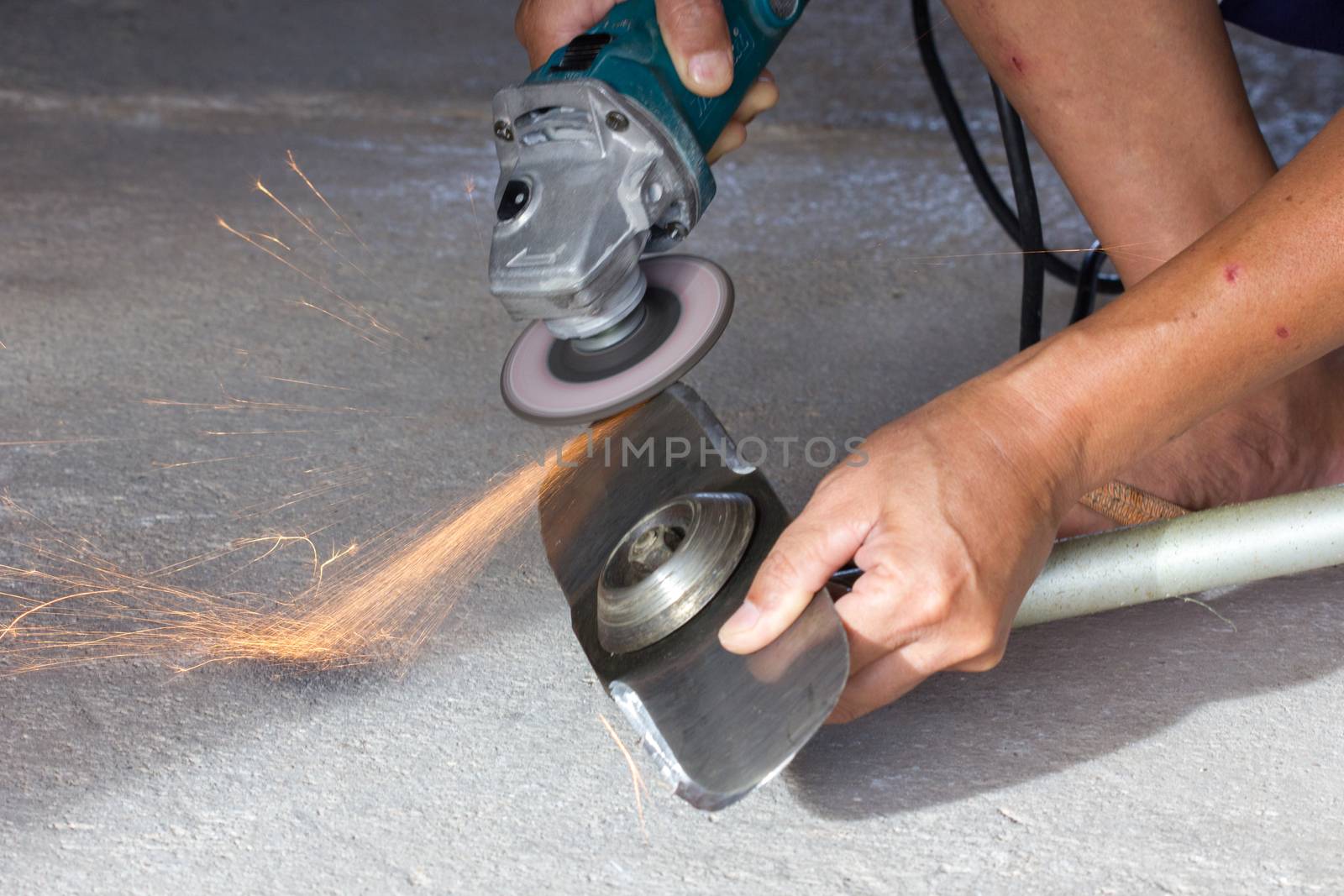 hand of man sharpening blade of mowing machine with angle-grinder