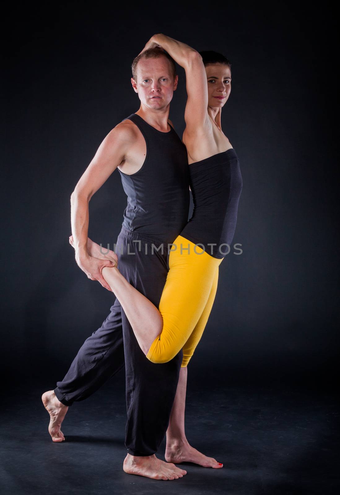 Young couple doing yoga. On the black backgraund