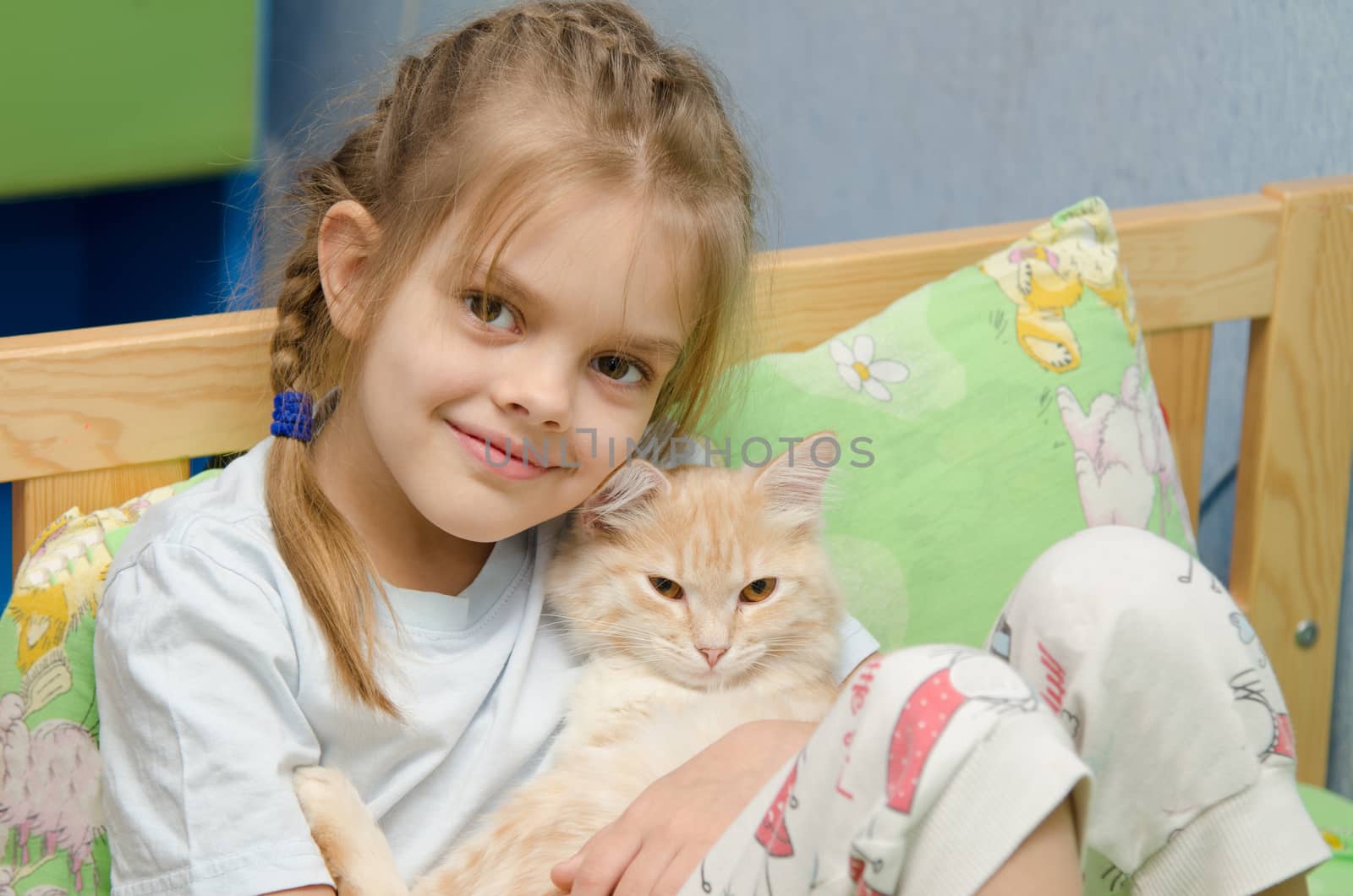 Six year old girl lying in bed with a young cat