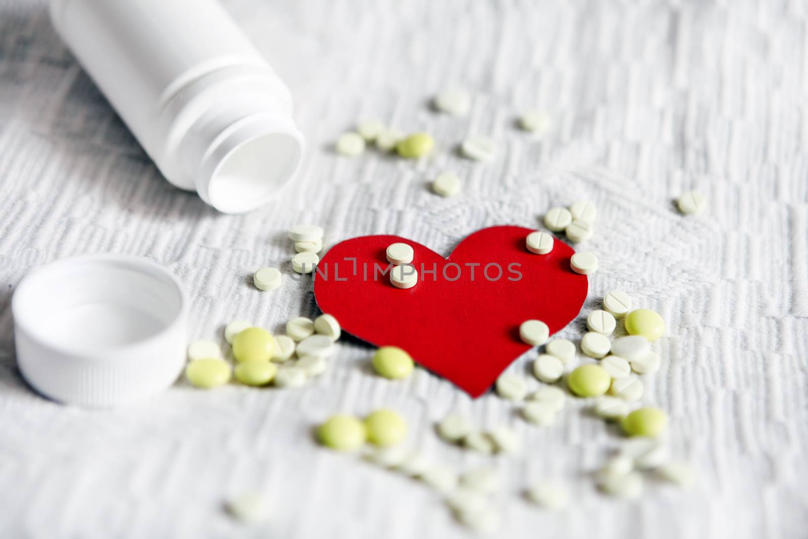 Heart Shape with the Pills on the White Fabric Background
