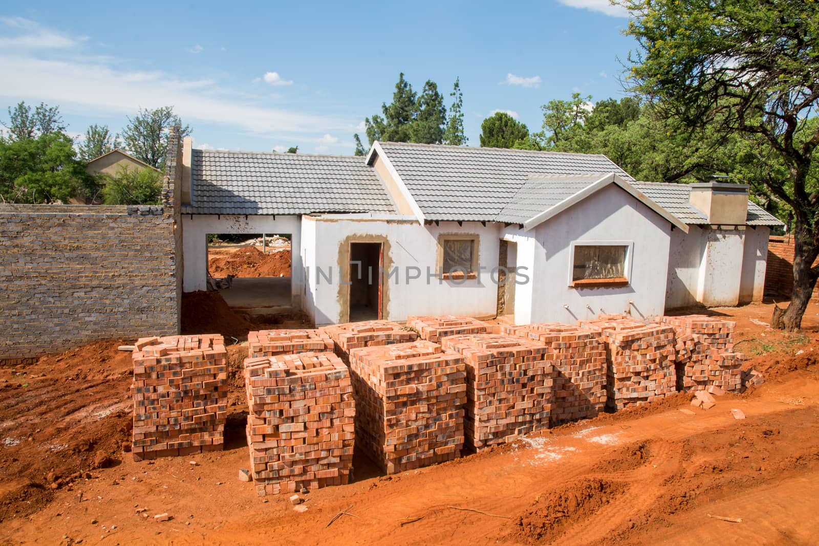 Stacked bricks in front of an incomplete house.