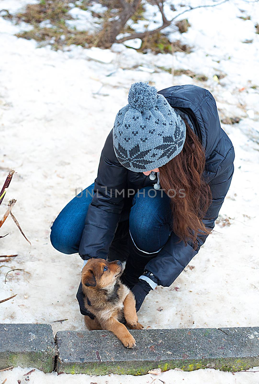 Happy girl playing with puppy in winter outdoors