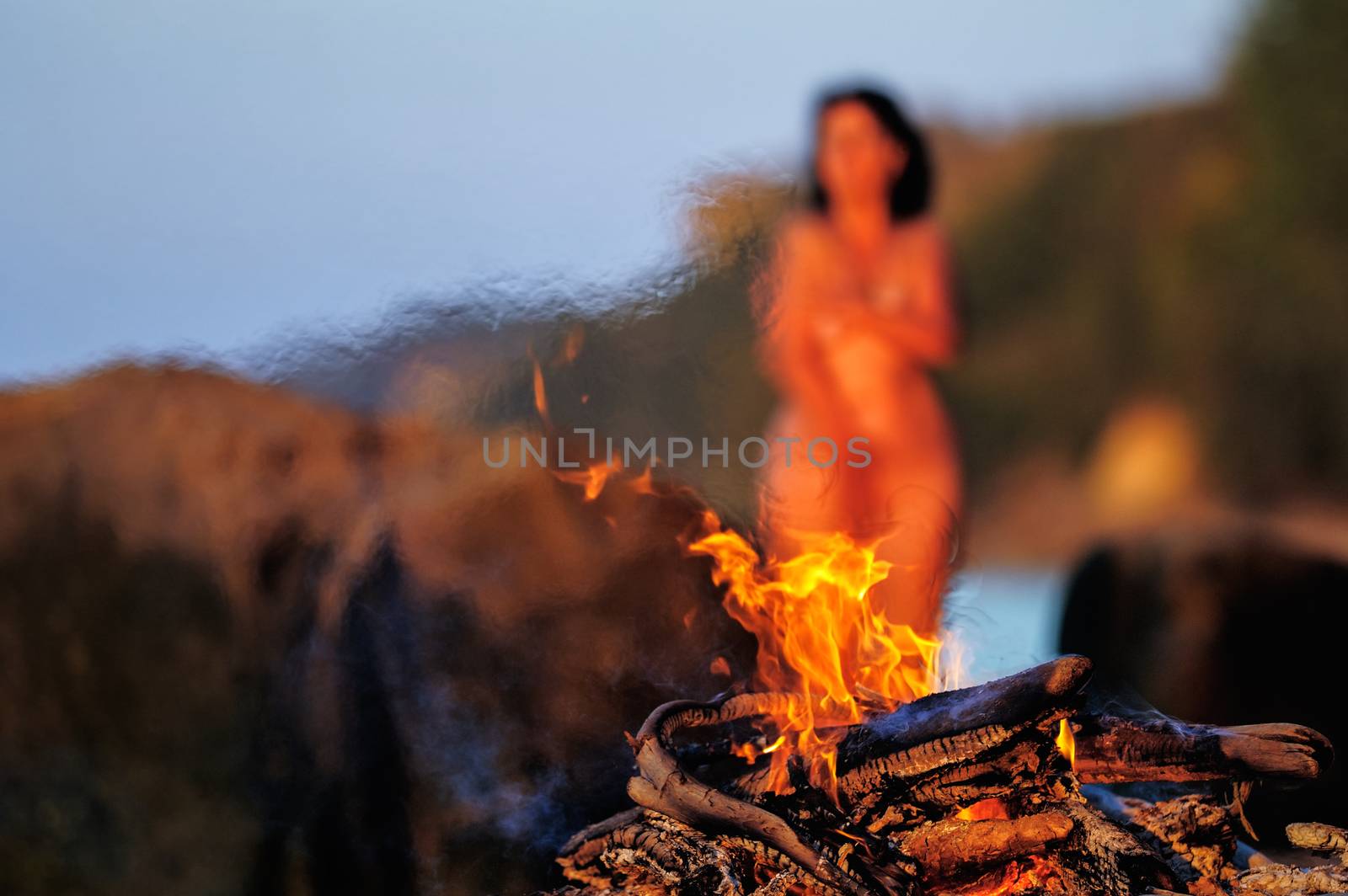 Nude woman on seashore near the bonfire