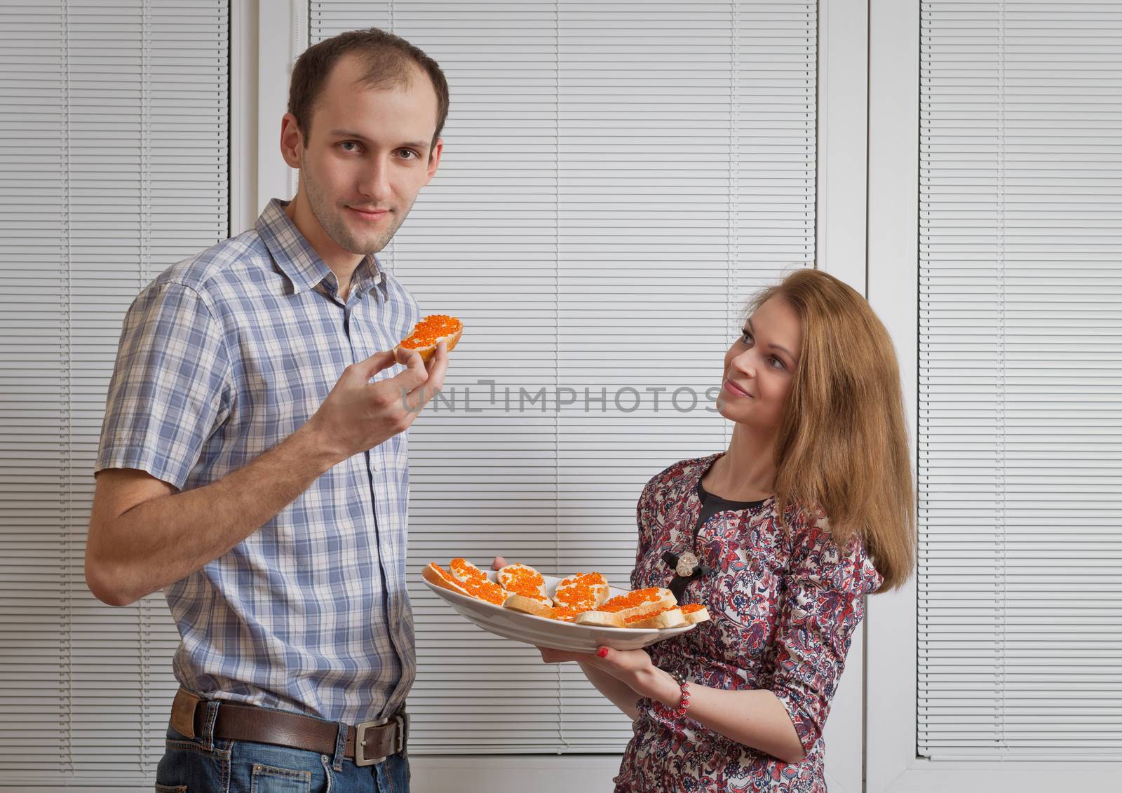 Nice girl with sandwiches treats the young man by fotooxotnik