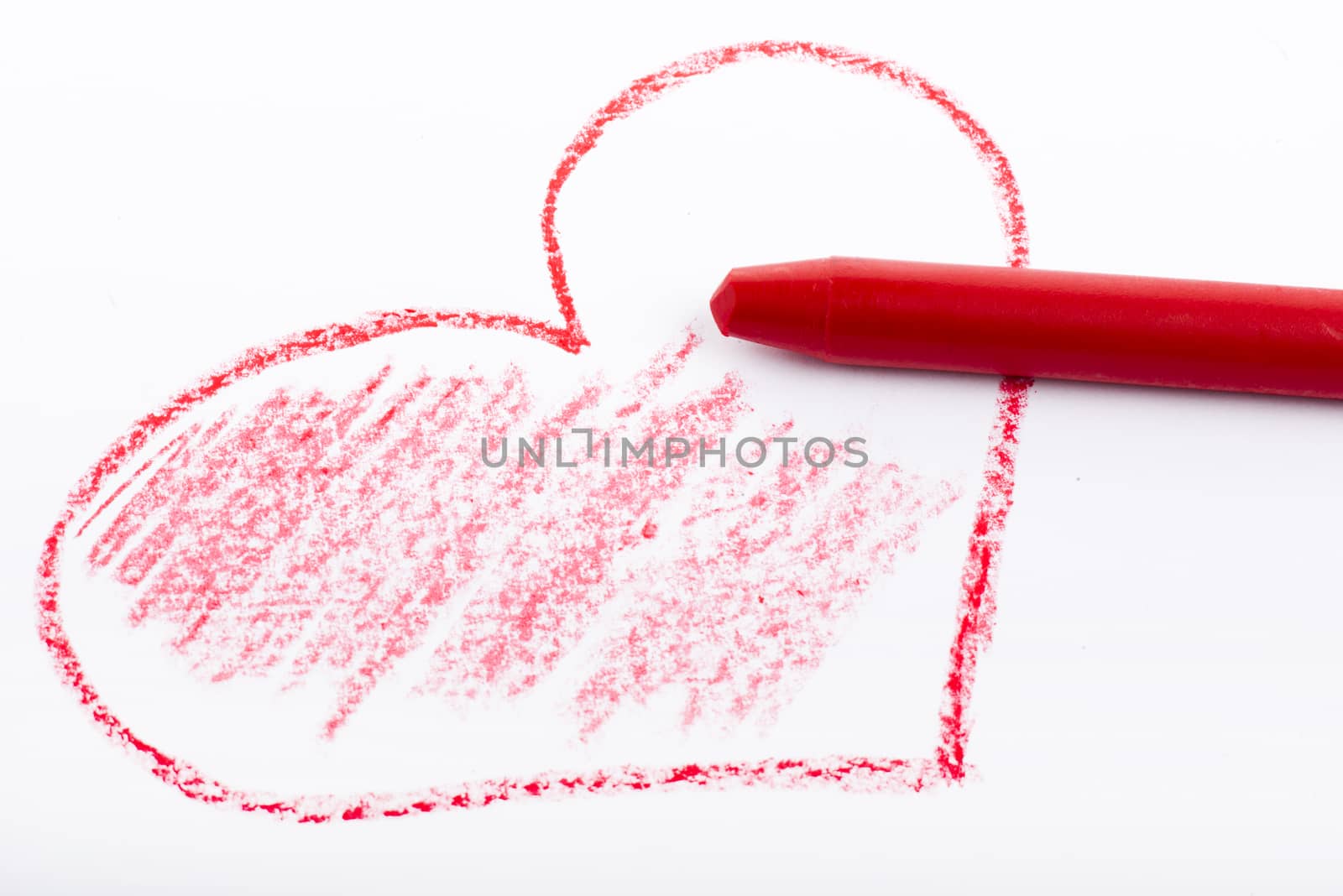 Closeup of a red pencil drawing a heart. On white paper.