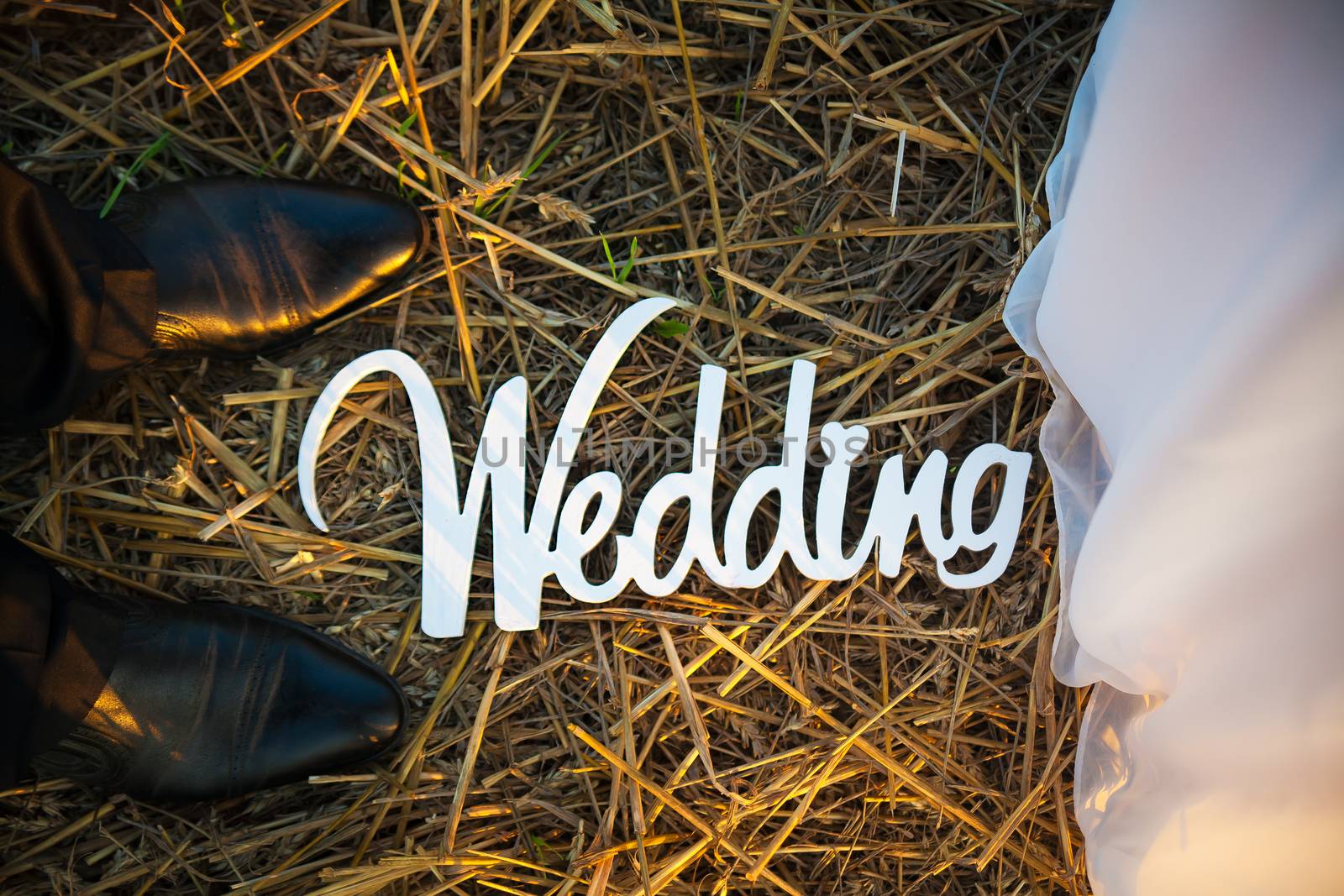 Feet of groom and bride and white wedding letters in straw