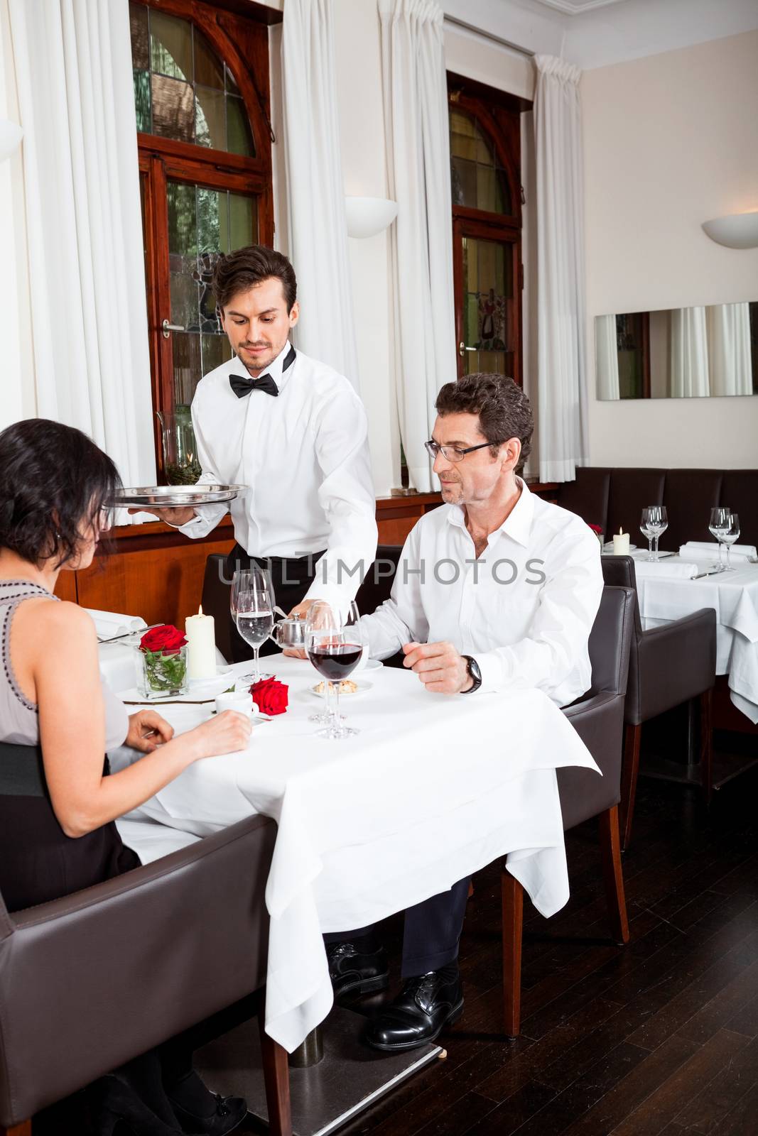 man and woman for dinner in restaurant waiter serving mineral water 