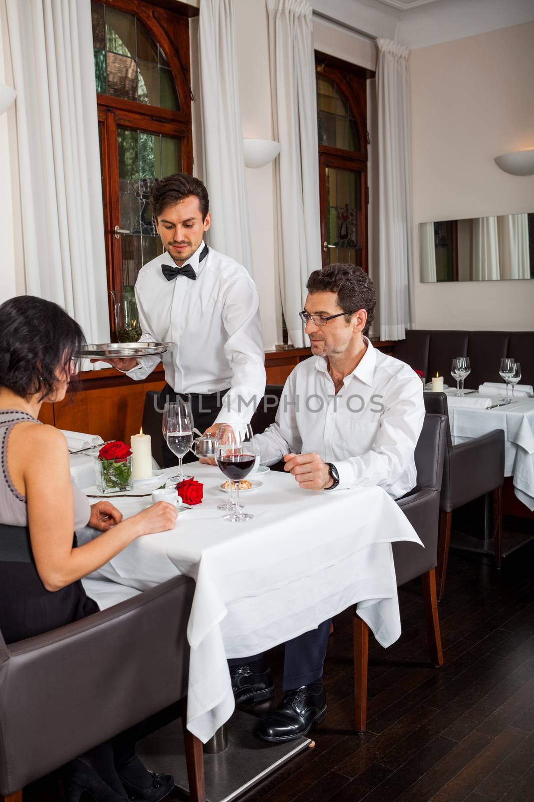 Waiter happily accommodating couple with a big smile on his face