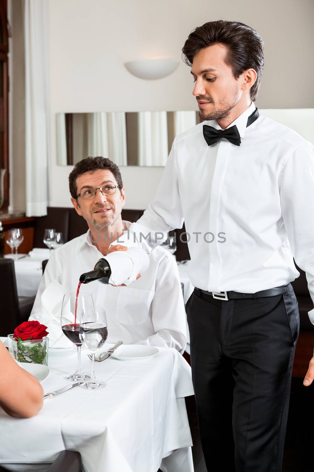 man and woman for dinner in restaurant waiter serving mineral water 