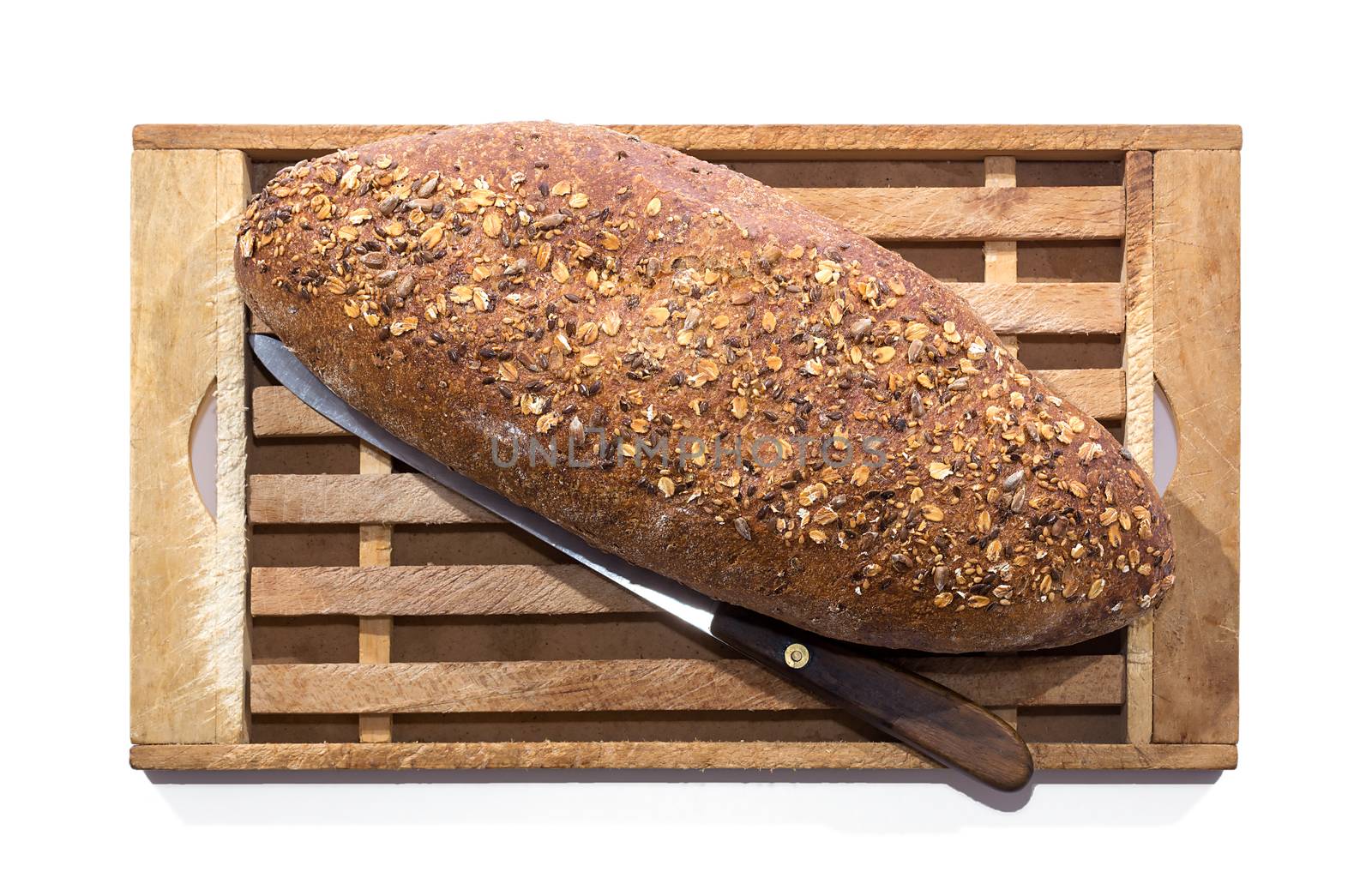 Whole Grain Bread and Vintage Knife on Wooden Cutting Board over white background, shot from above