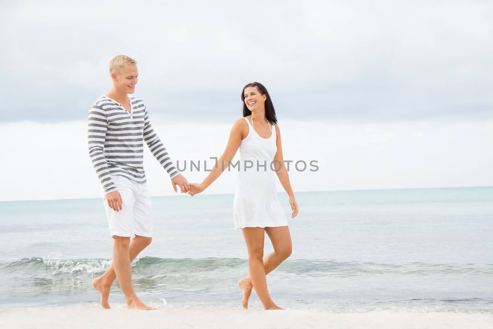 Couple holding hands while walking on the beach by juniart