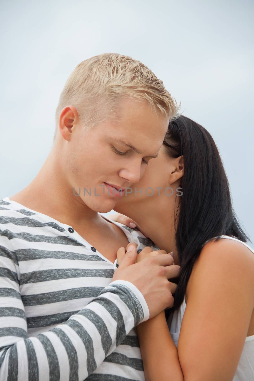 Loving couple enjoy a quiet tender moment as they stand in a close embrace staring off to the left of the frame in contentment