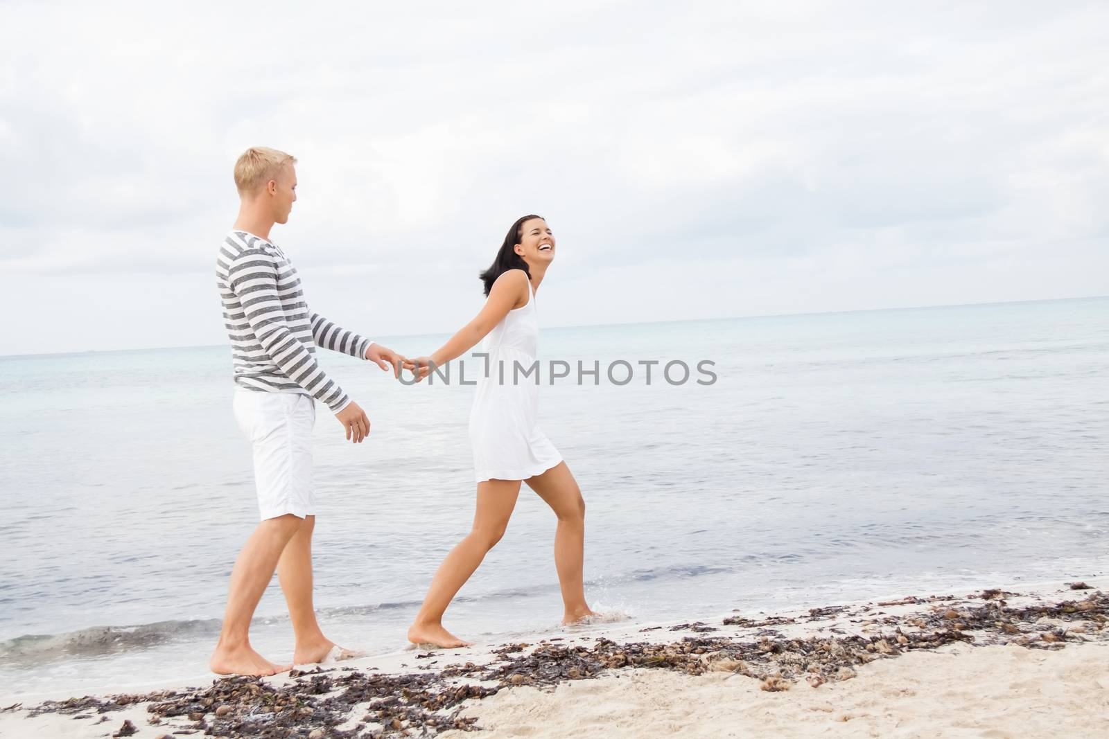 Couple holding hands while walking on the beach by juniart