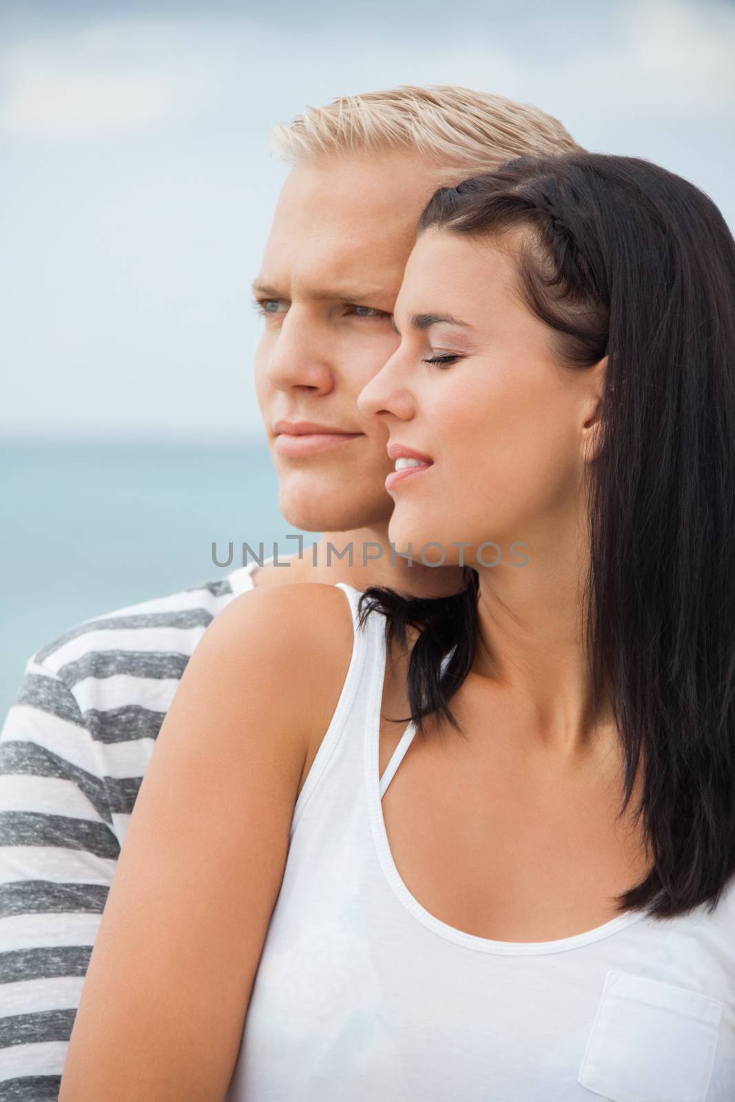 Loving couple enjoy a quiet tender moment as they stand in a close embrace staring off to the left of the frame in contentment