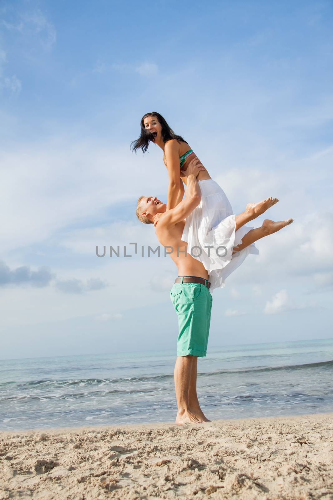 smiling young couple having fun in summer on the beach