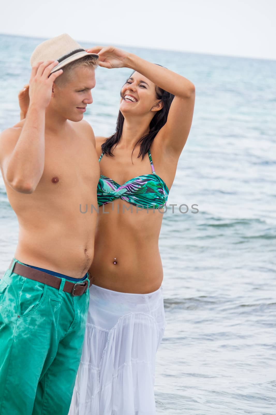 smiling young couple having fun in summer on the beach