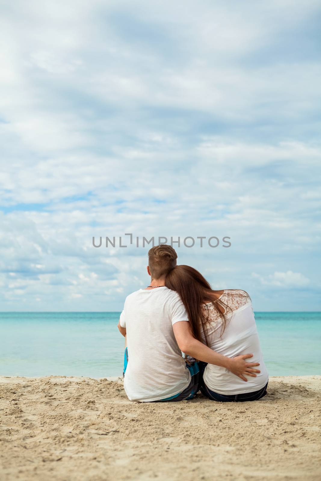 romantic young couple sitting on the beach in summer by juniart