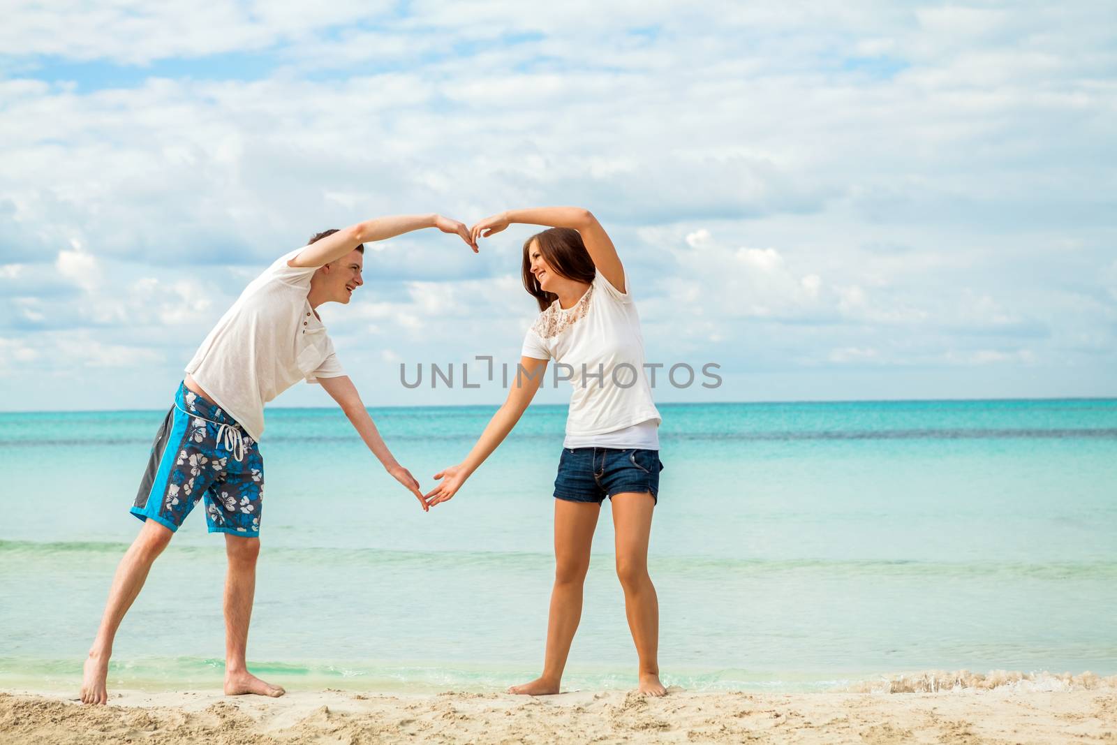 smiling young couple having fun in summer holiday heart symbol