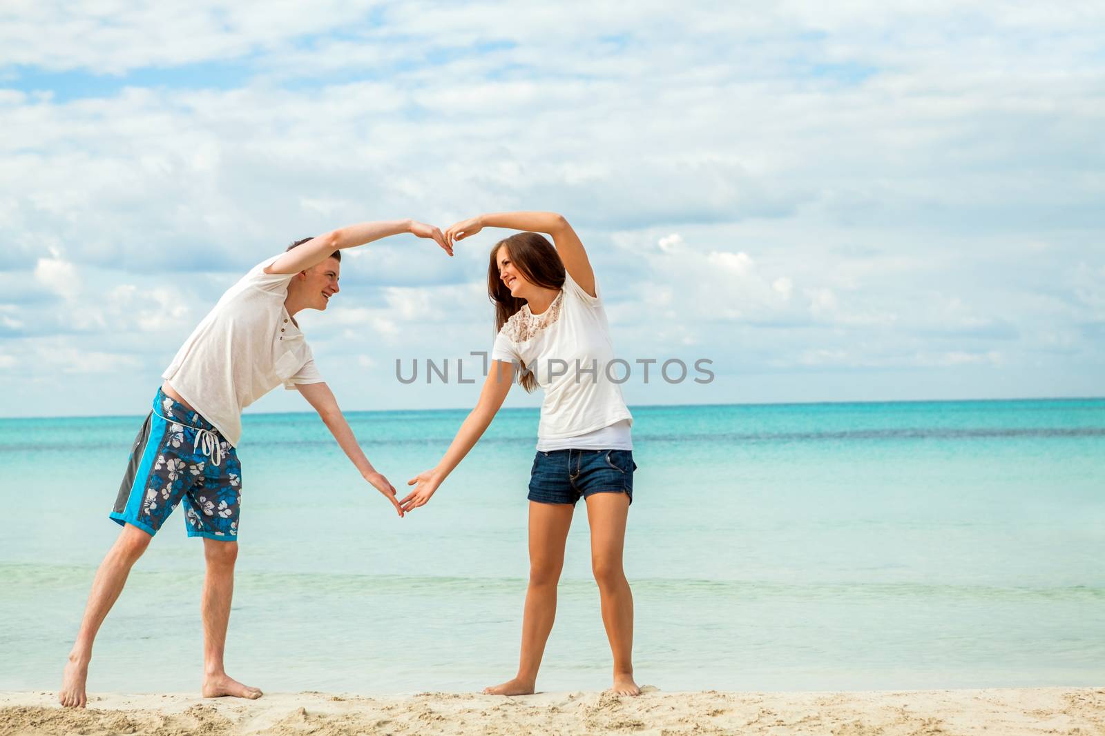 smiling young couple having fun in summer holiday heart symbol