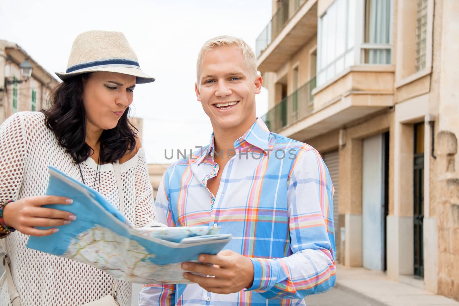 Trendy attractive young couple of tourists consulting a map as they search for their destination while out sightseeing on their summer vacation