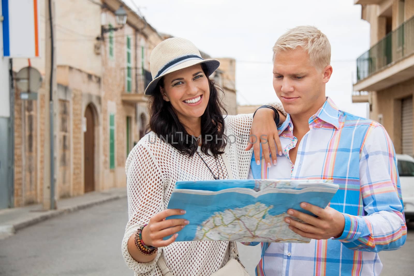 Trendy attractive young couple of tourists consulting a map as they search for their destination while out sightseeing on their summer vacation
