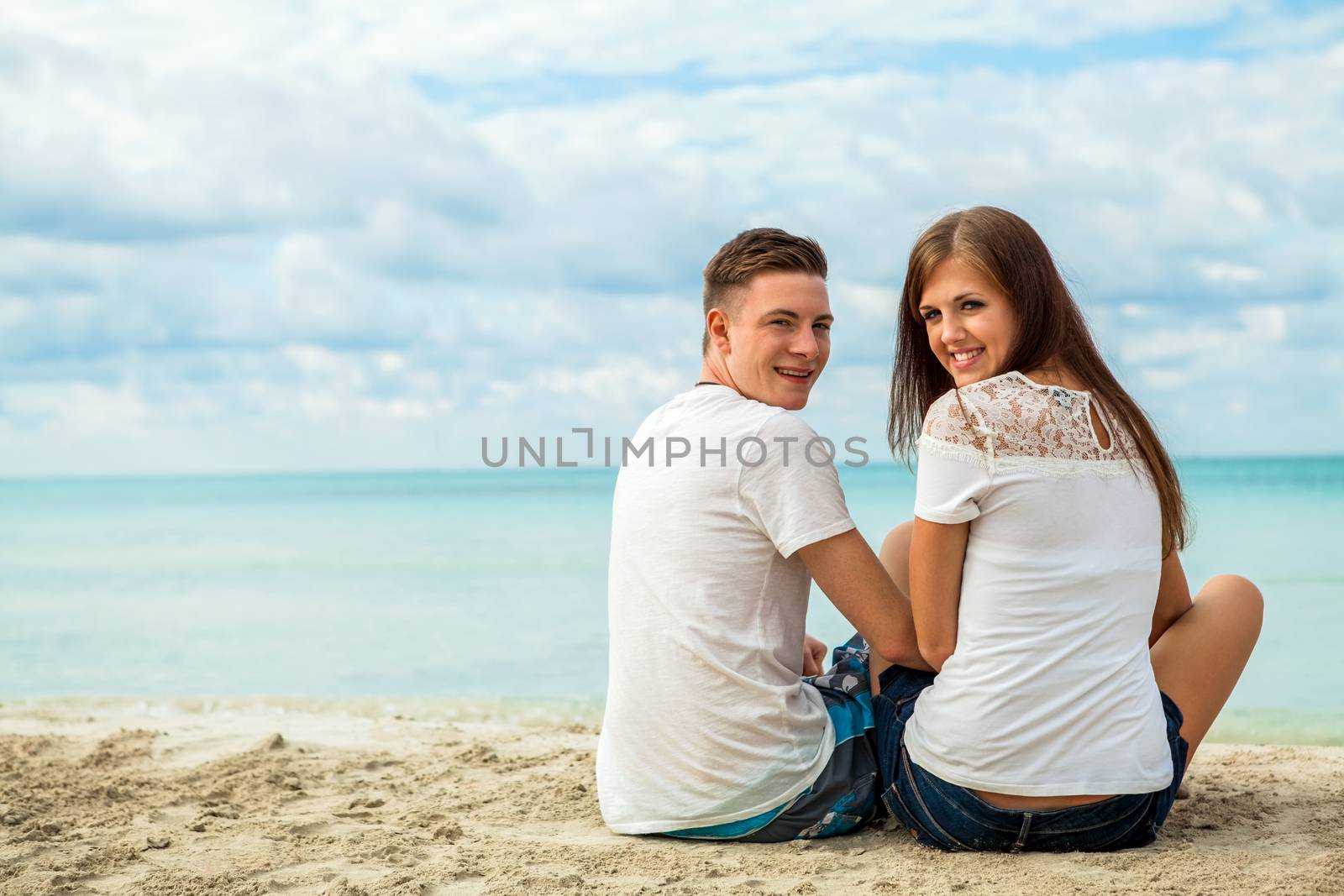 romantic young couple sitting on the beach in summer by juniart