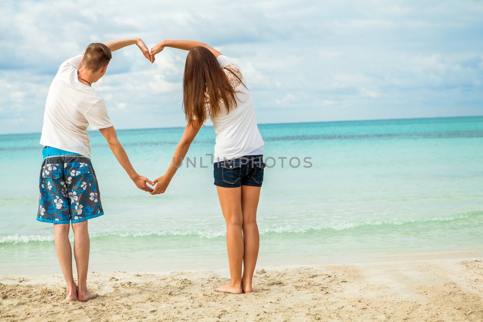 smiling young couple having fun in summer holiday heart symbol