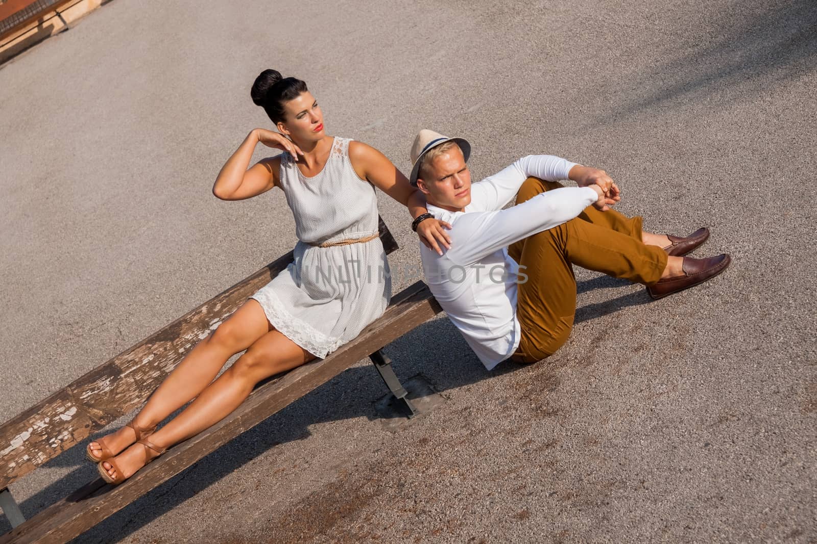 Elegant trendy young couple in fashionable modern clothes and accessories posing outdoors in the summer sunshine in a garden or park