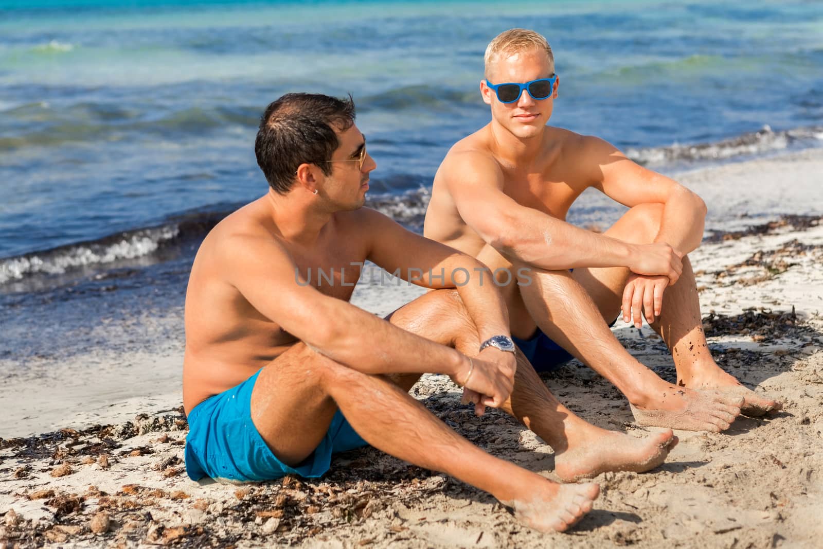 Two handsome young men chatting on a beach by juniart