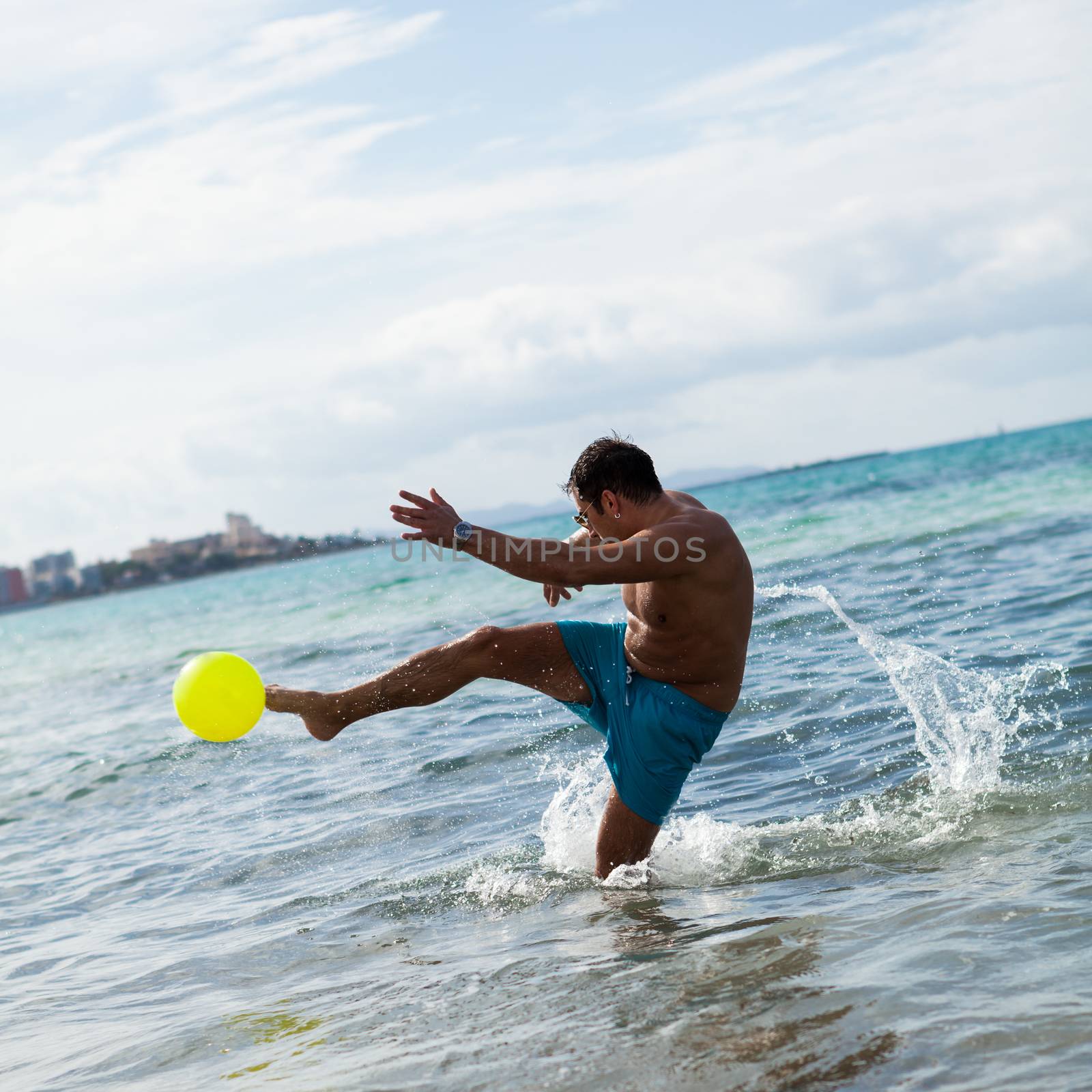 happy young adult man playing beach ball in summer sand fun sport