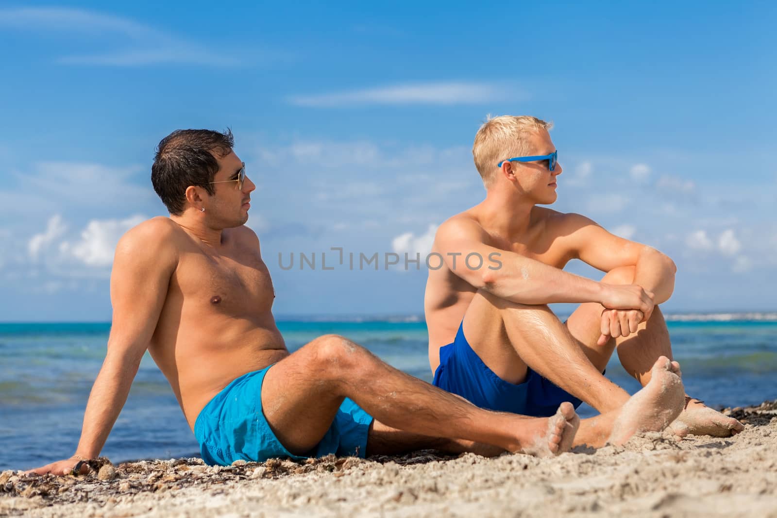 Two handsome young men chatting on a beach by juniart