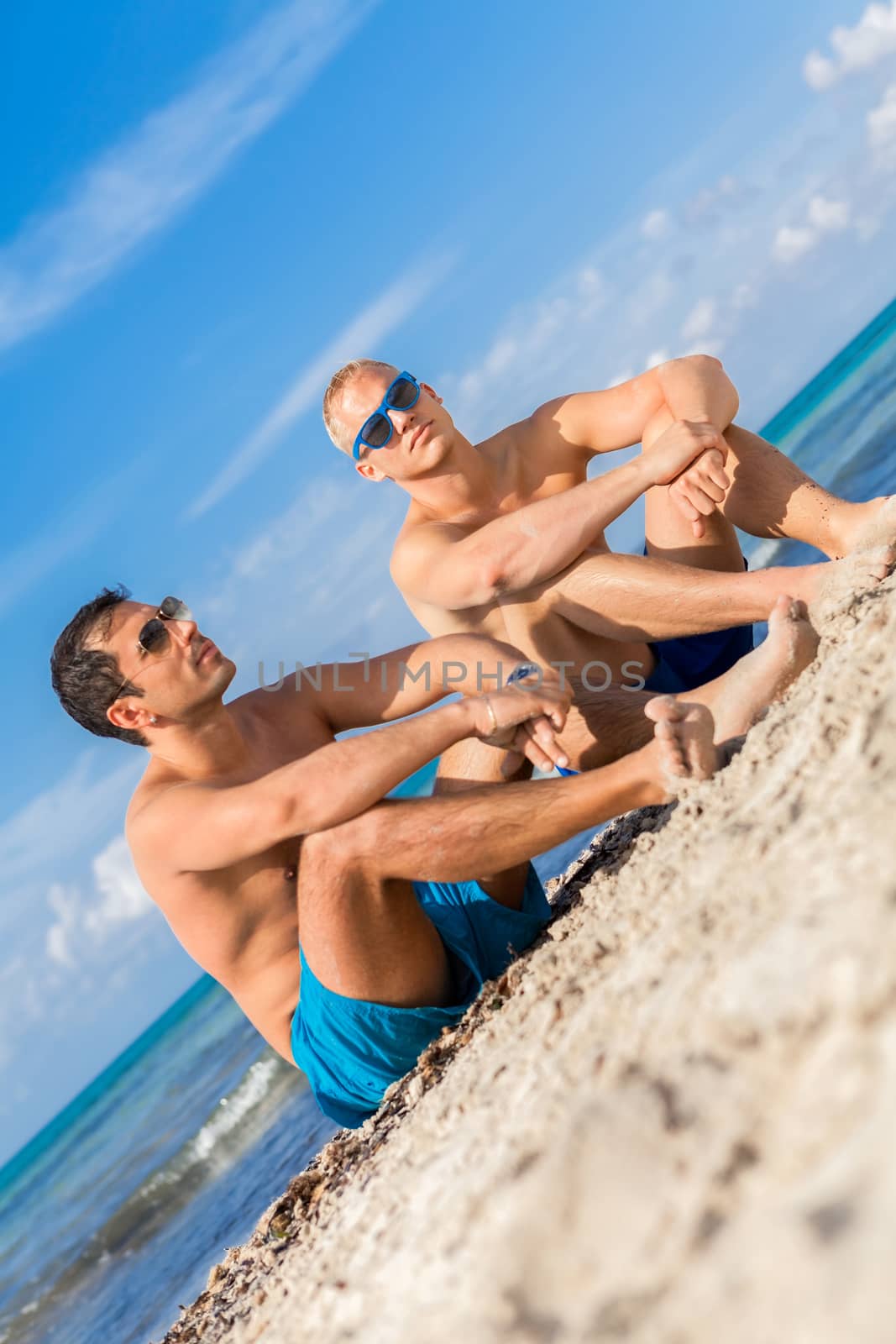 Two handsome young men chatting on a beach by juniart