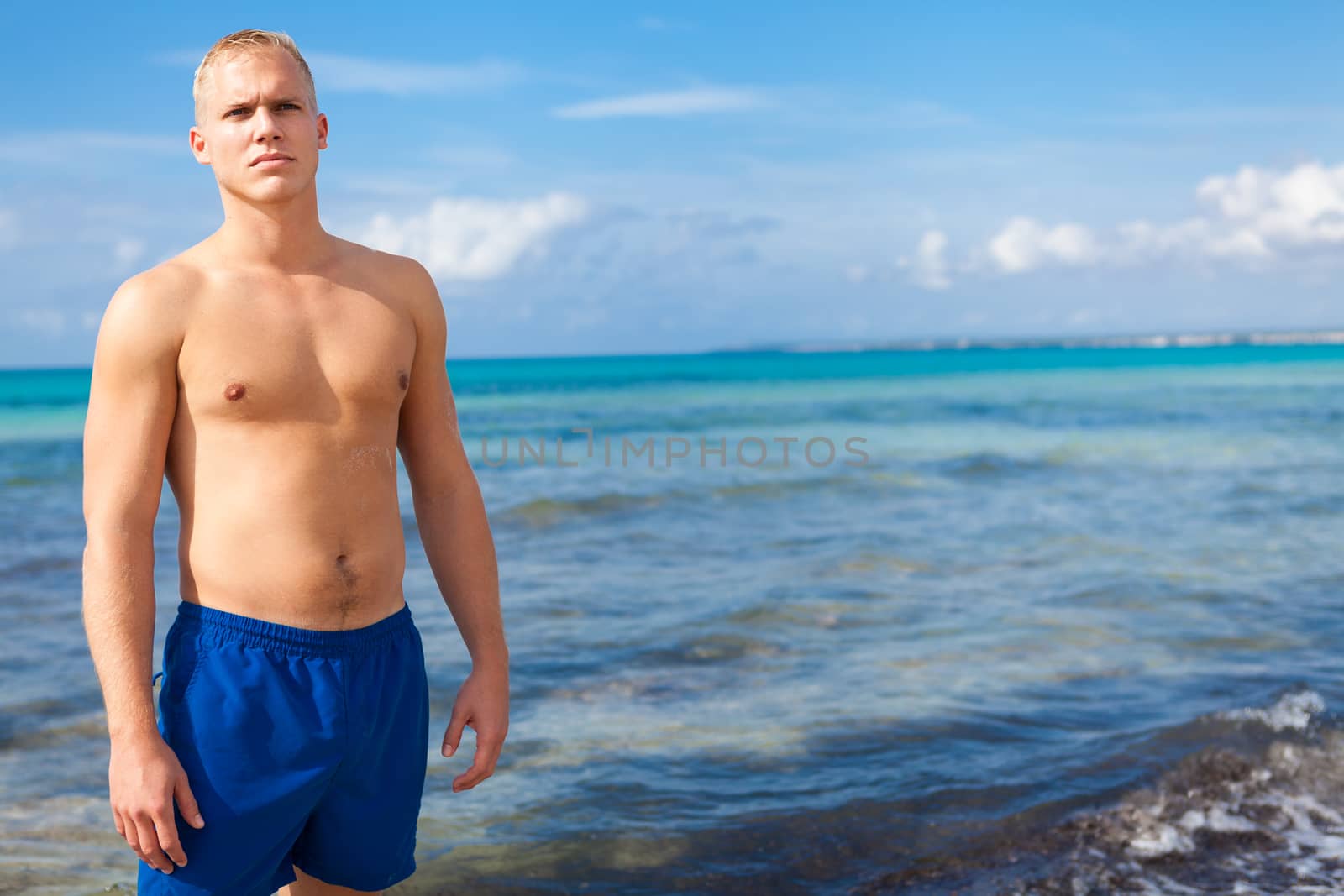 attractive young athletic man on the beach in summer outdoor vacation