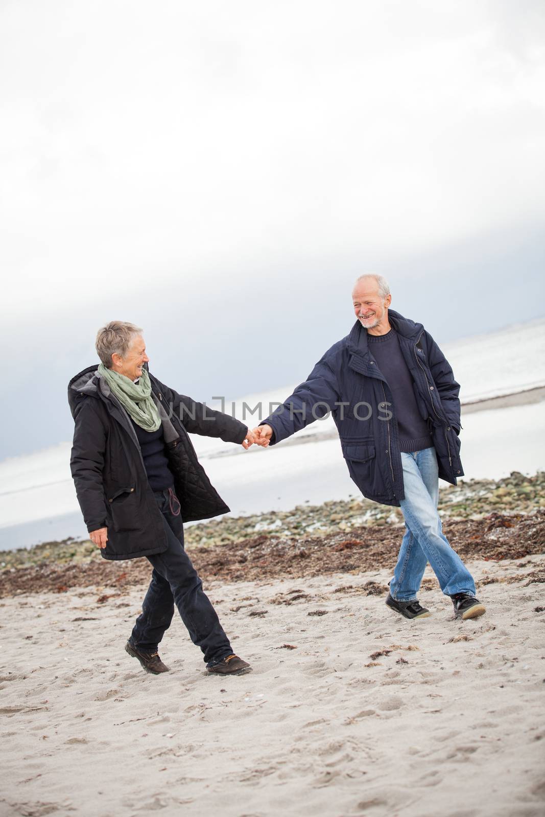 mature happy couple walking on beach in autumn lifestyle healthy