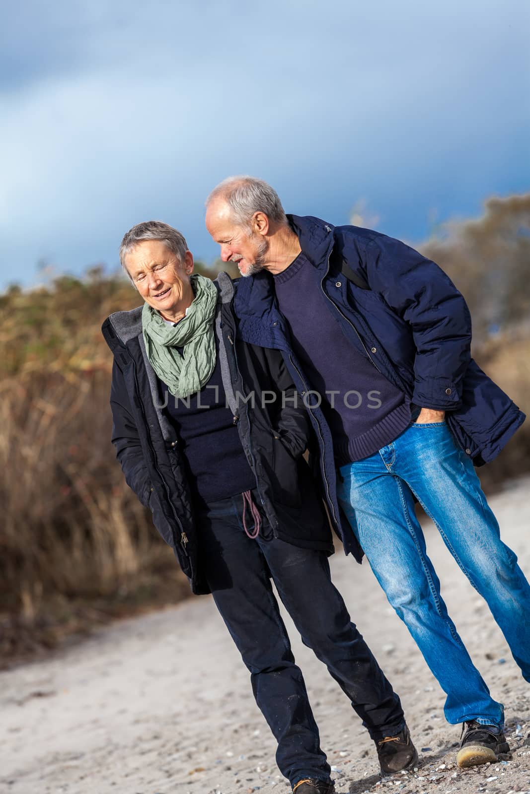 mature senior couple walking on the beach autumn winter lifestyle healthy
