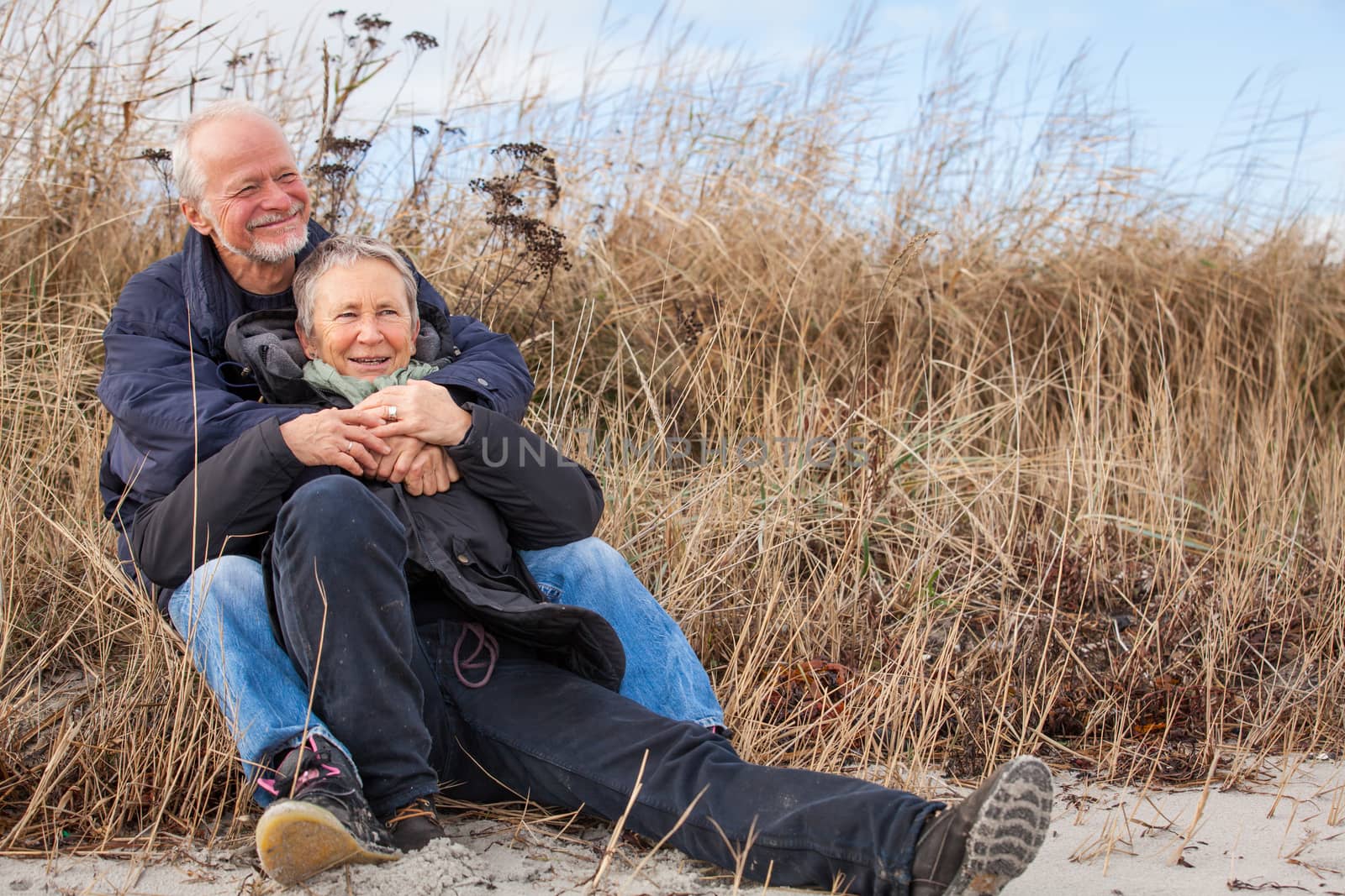 happy mature couple relaxing baltic sea dunes  by juniart