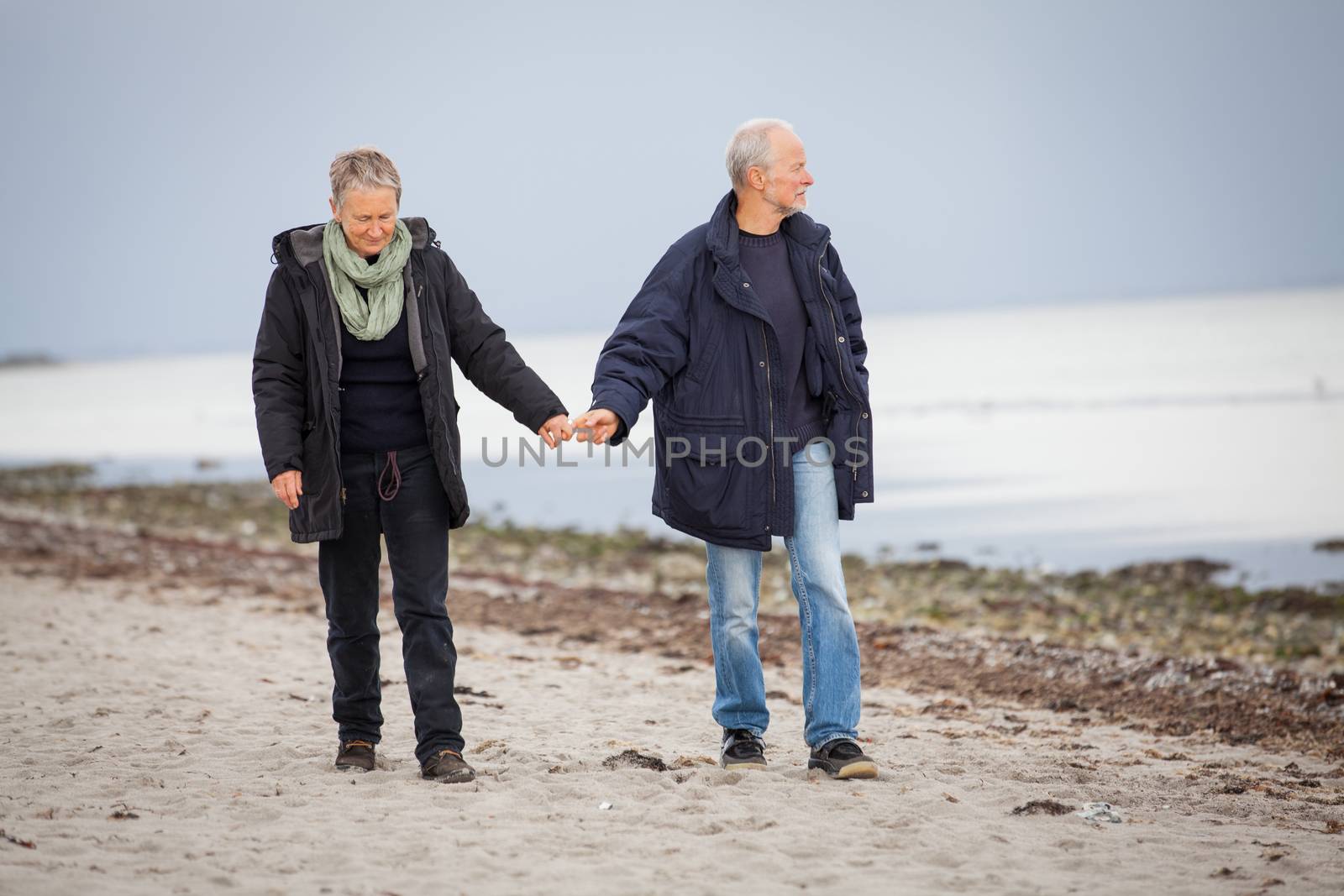 mature happy couple walking on beach in autumn lifestyle healthy