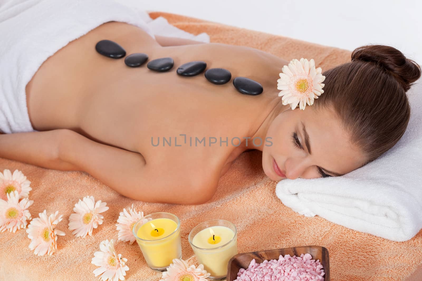 young attractive woman get hot stone massage by professional in wellness spa salon