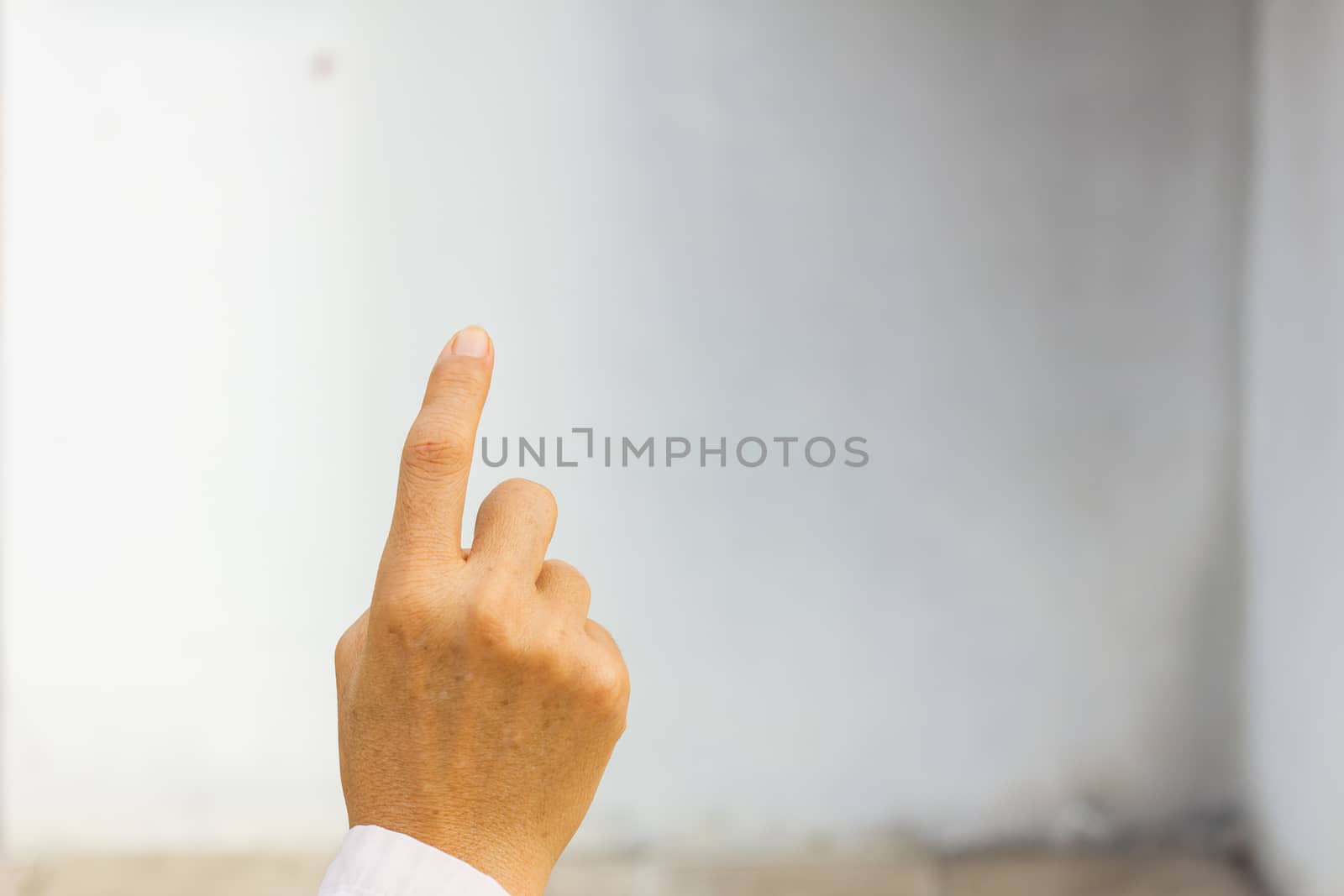 Hand simulating pressing a button on blank white wall