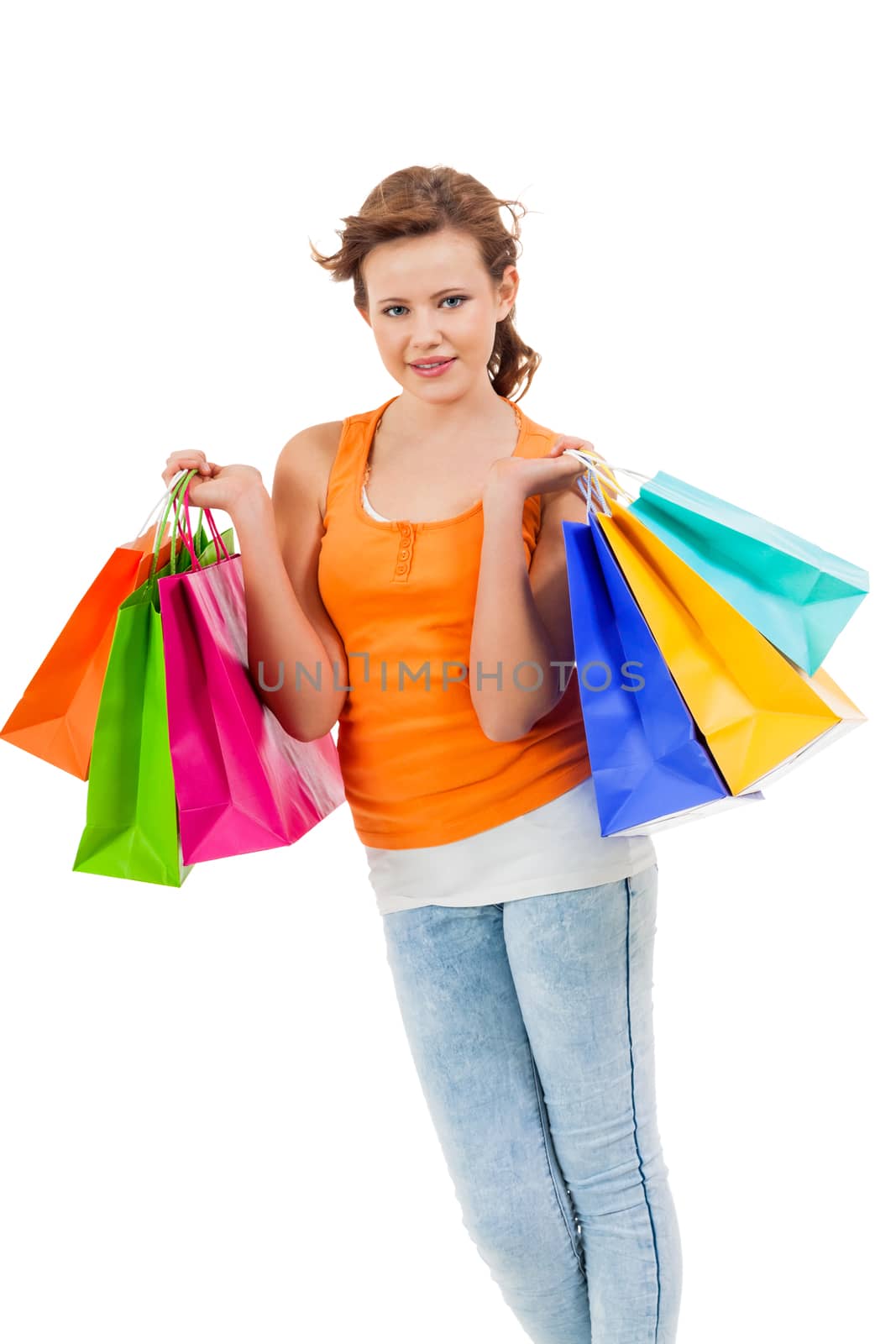 Happy attractive young shopaholic with her hands full of brightly coloured shopping bags from the seasonal sales standing smiling at the camera, isolated on white